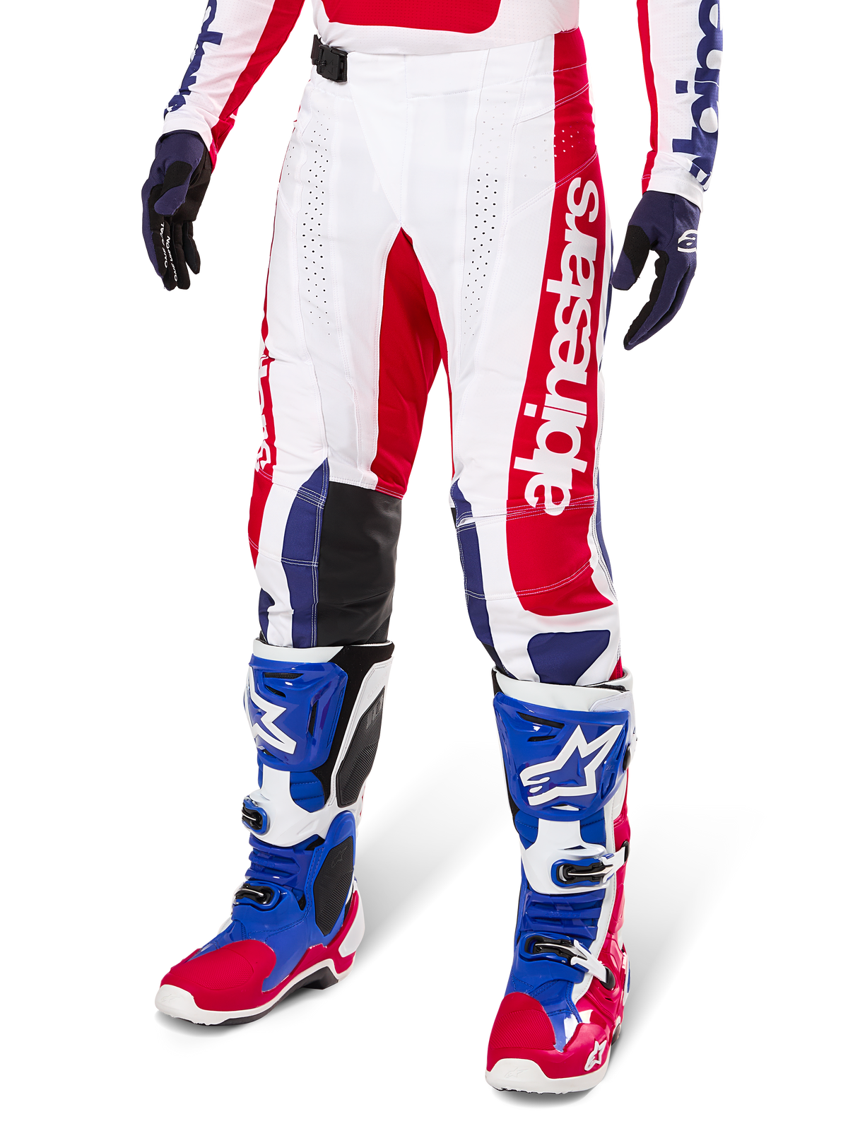 Alpinestars Limited Edition Techstar Fortitude crossbroek, rood, wit en blauw kleurenschema, gedragen met bijpassende motorcrosslaarzen en handschoenen, met verticale Alpinestars-branding, sportieve pasvorm voor off-road racen