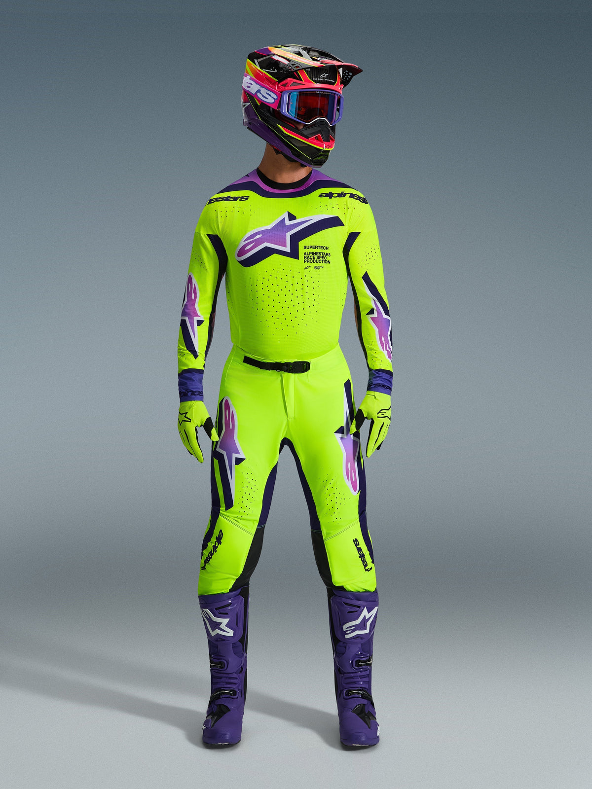 Motocross-rijder in de Alpinestars 2026 Supertech Vista Jersey in felgeel met paarse en zwarte accenten, bijpassende gele en paarse broek, paarse laarzen en bijbehorende helm en handschoenen, complete professionele race-uitrusting