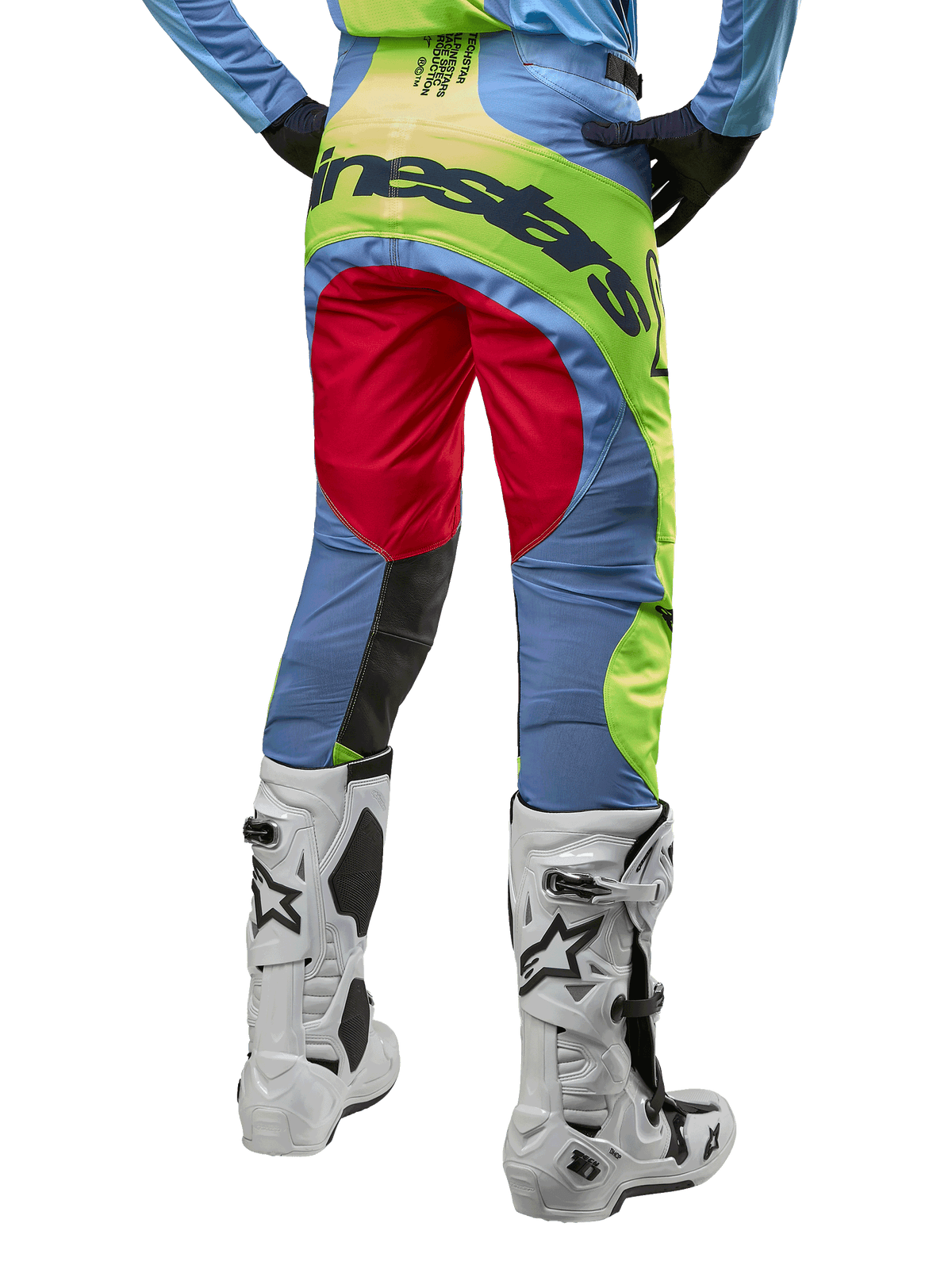 Alpinestars 2024 Techstar Ocuri crossbroek, motorcrossbroek, lichtblauw met fluogeel en bessenrood, achteraanzicht gedragen met witte en zwarte motorcrosslaarzen, voorzien van opvallende kleurvlakken en een groot Alpinestars-logo op het zitvlak
