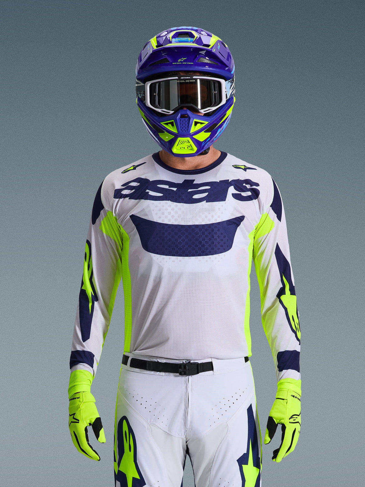 Alpinestars 2026 Racer Air Riway Jersey, Light Gray with Dark Blue astars logo, Fluo Yellow and Blue accents on sleeves, worn by a motocross rider with matching purple and neon yellow helmet and gloves, technical mesh fabric for off-road racing.