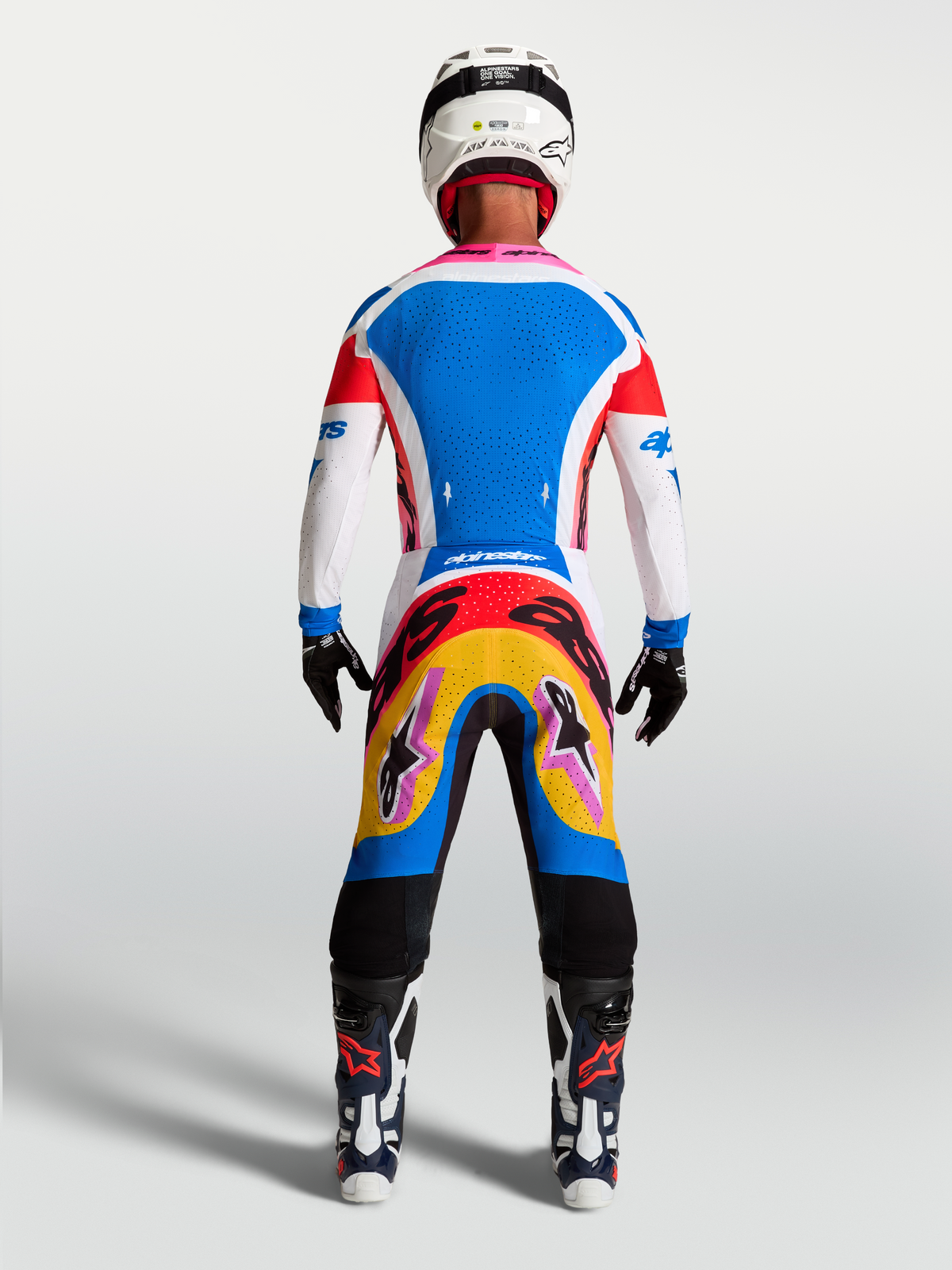 Alpinestars Supertech Dyna jersey en gearset, blauw-witte motorcrossuitrusting, achteraanzicht op model met roze accenten.