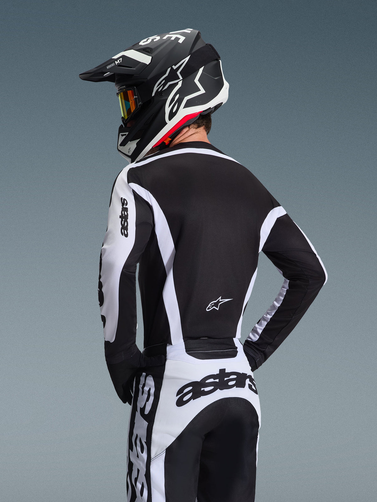 Alpinestars 2026 Racer Riway Gear Set, Motocross rider seen from the back wearing a black and white technical jersey and pants, coordinated black and white helmet with goggles, bold astars branding on sleeves and rear, designed for off-road performance