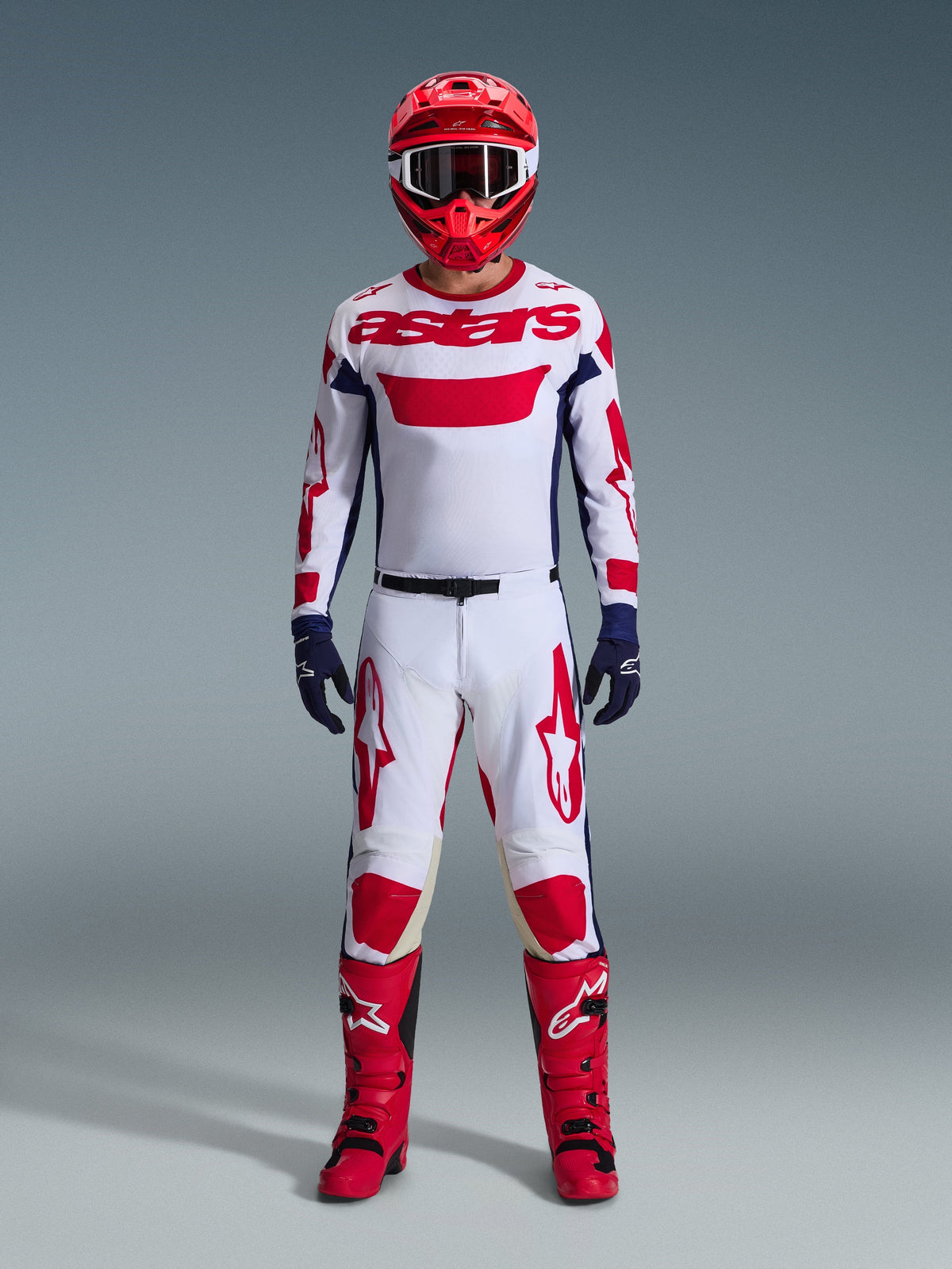 Alpinestars motorcrosser in volledige race-uitrusting, 2026 Racer Riway Jersey in wit blauw rood, bijpassende wit-rode broek, rode helm, rode laarzen en marineblauwe handschoenen, gecoördineerde outfit voor off-road racen