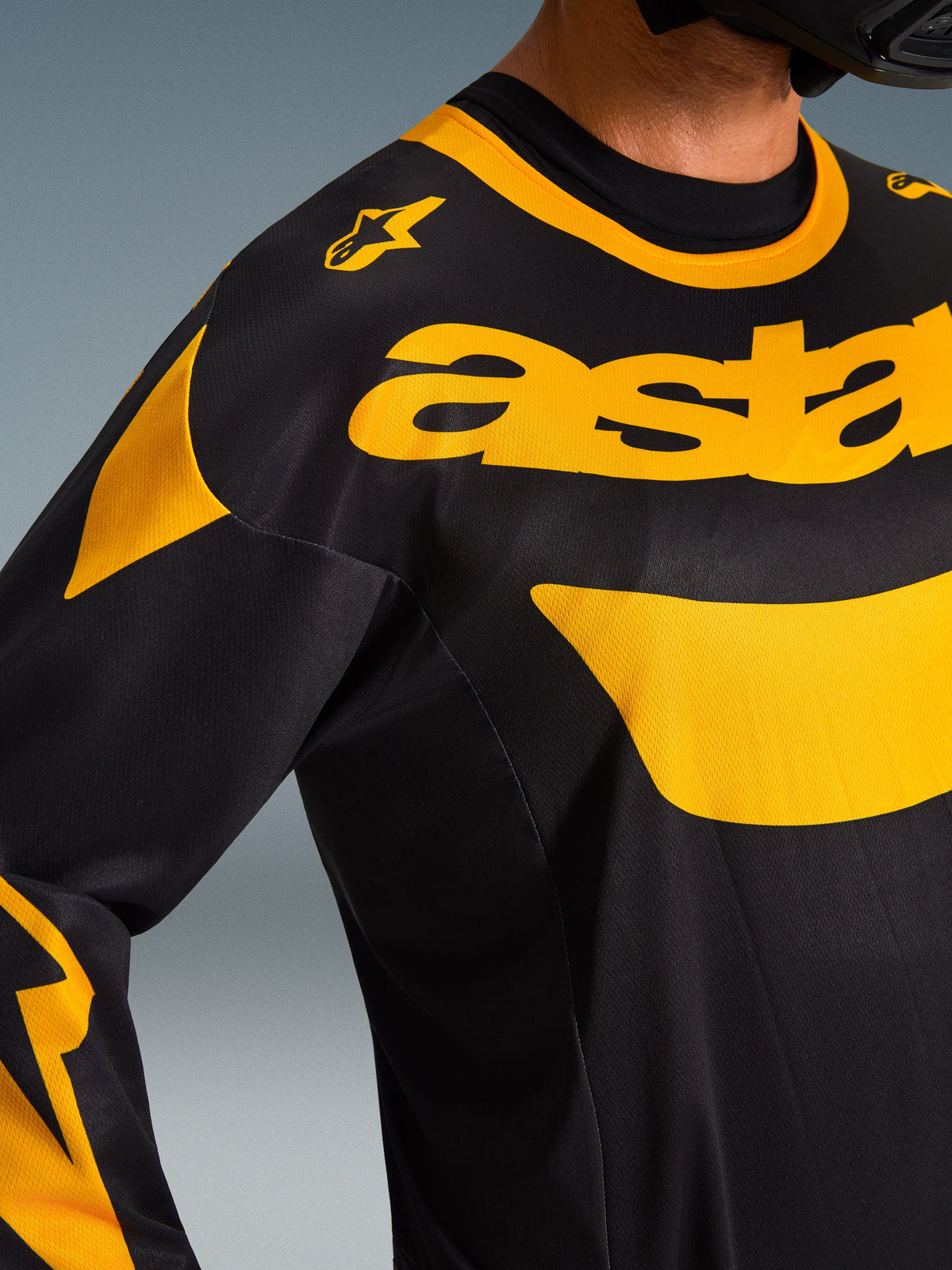 Close-up van Alpinestars 2026 Racer Riway Jersey, zwart en geel, met opvallende gele branding op de borst, technische mesh-stof voor ventilatie, hoogwaardige motorcrosskleding