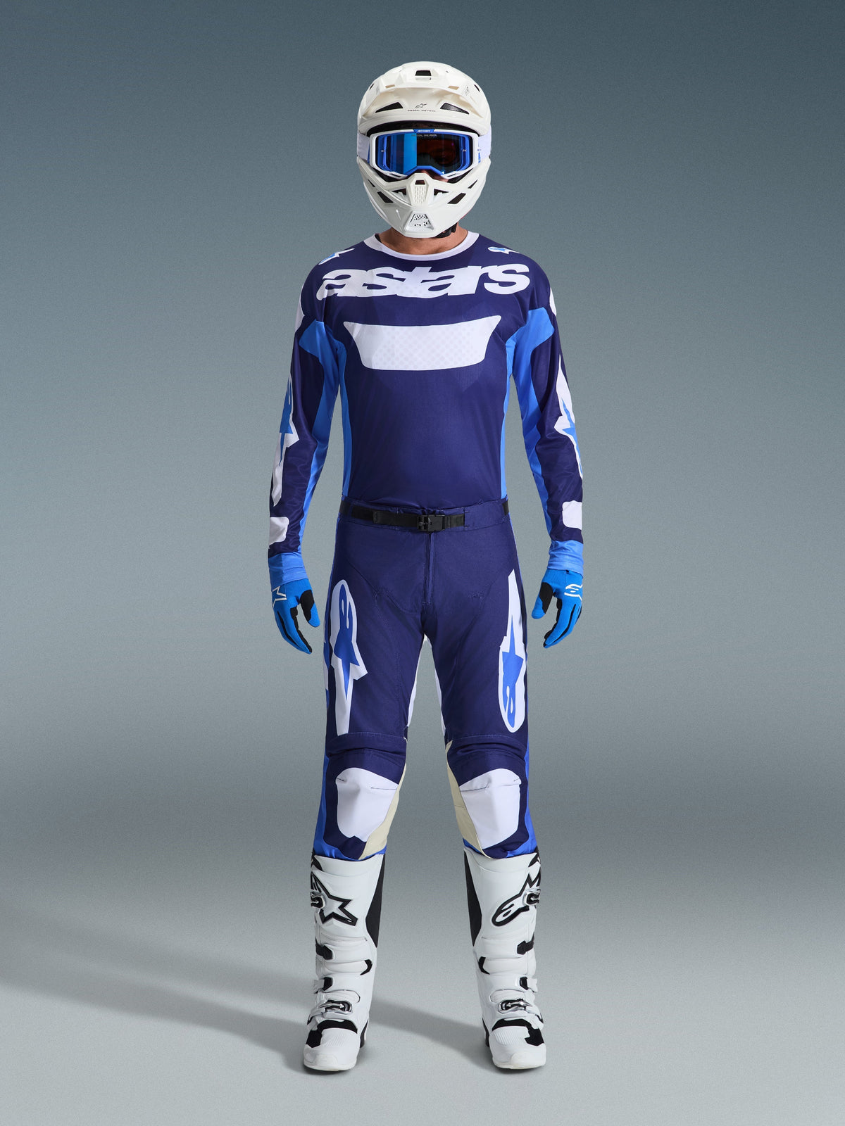 Alpinestars motorcrosser in volledige race-uitrusting, 2026 Racer Riway Jersey in UCLA Blue en wit met navy panelen en 'astars' branding op de borst, bijpassende blauw-witte broek, witte helm met blauwe crossbril, wit-zwarte laarzen en blauwe handschoenen, gecoördineerde motorcross-set.