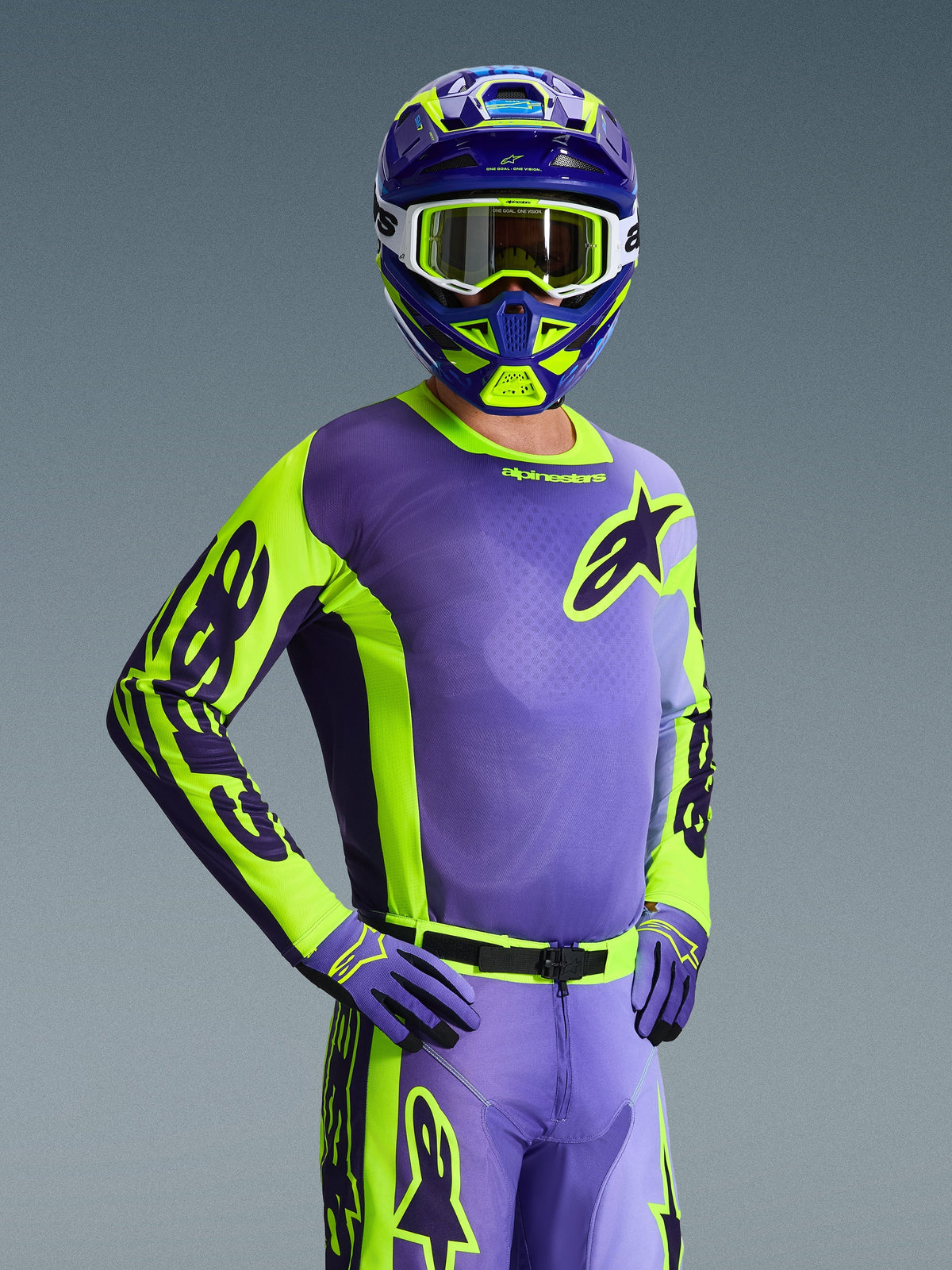 Motocrossrijder in de 2026 Racer Portl Jersey, paars en neon geel, bijpassende paarse en gele helm met witte crossbril, paarse en gele handschoenen, gecoördineerde volledige uitrusting voor off-road racing