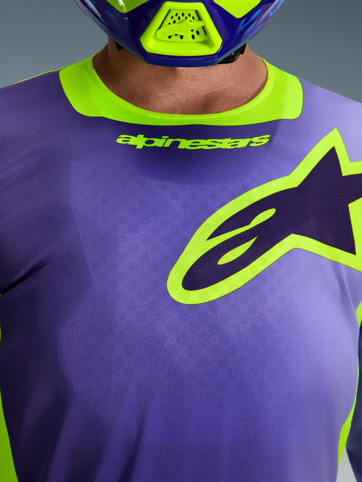 Alpinestars 2026 Racer Portl Jersey, motocross shirt, paars en fluor geel, close-up van de borst met een groot geel omlijnd Alpinestars-logo, stretchkraag met merknaam, technisch vochtafvoerend polyfabric