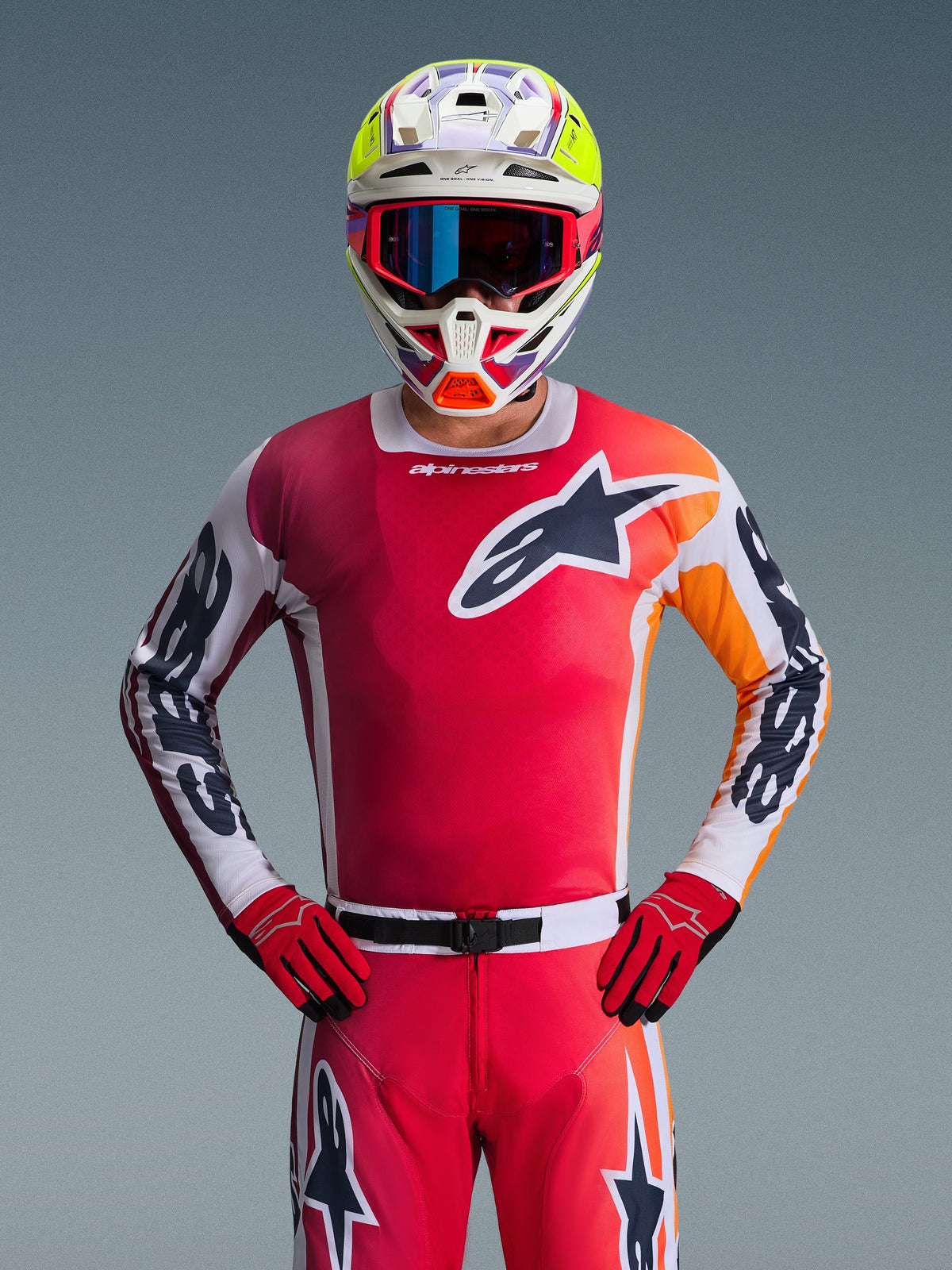 Alpinestars 2026 Racer Portl Jersey, rood motorcross shirt, vooraanzicht van een rijder die een bijpassende rode broek en handschoenen draagt, voorzien van een zwart-wit sterlogo op de borst en witte mouwen met zwarte branding, gecombineerd met een meerkleurige wit-gele helm, complete professionele off-road race-uitrusting