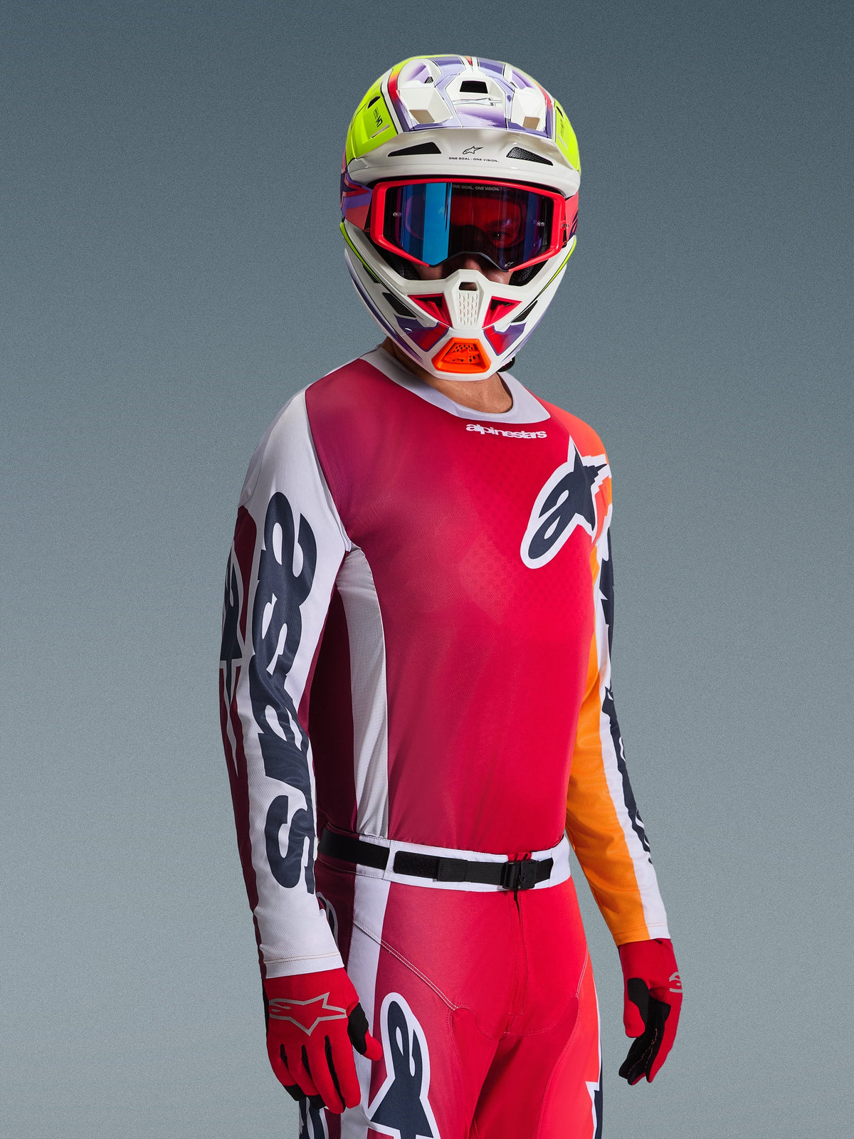 Motorcrossrijder die de 2026 Racer Portl Jersey draagt, rood met witte en donkergrijze mouwen, gecombineerd met bijpassende motorcrossbroek, veelkleurige helm met blauwe crossbril en rode handschoenen, studio-opname
