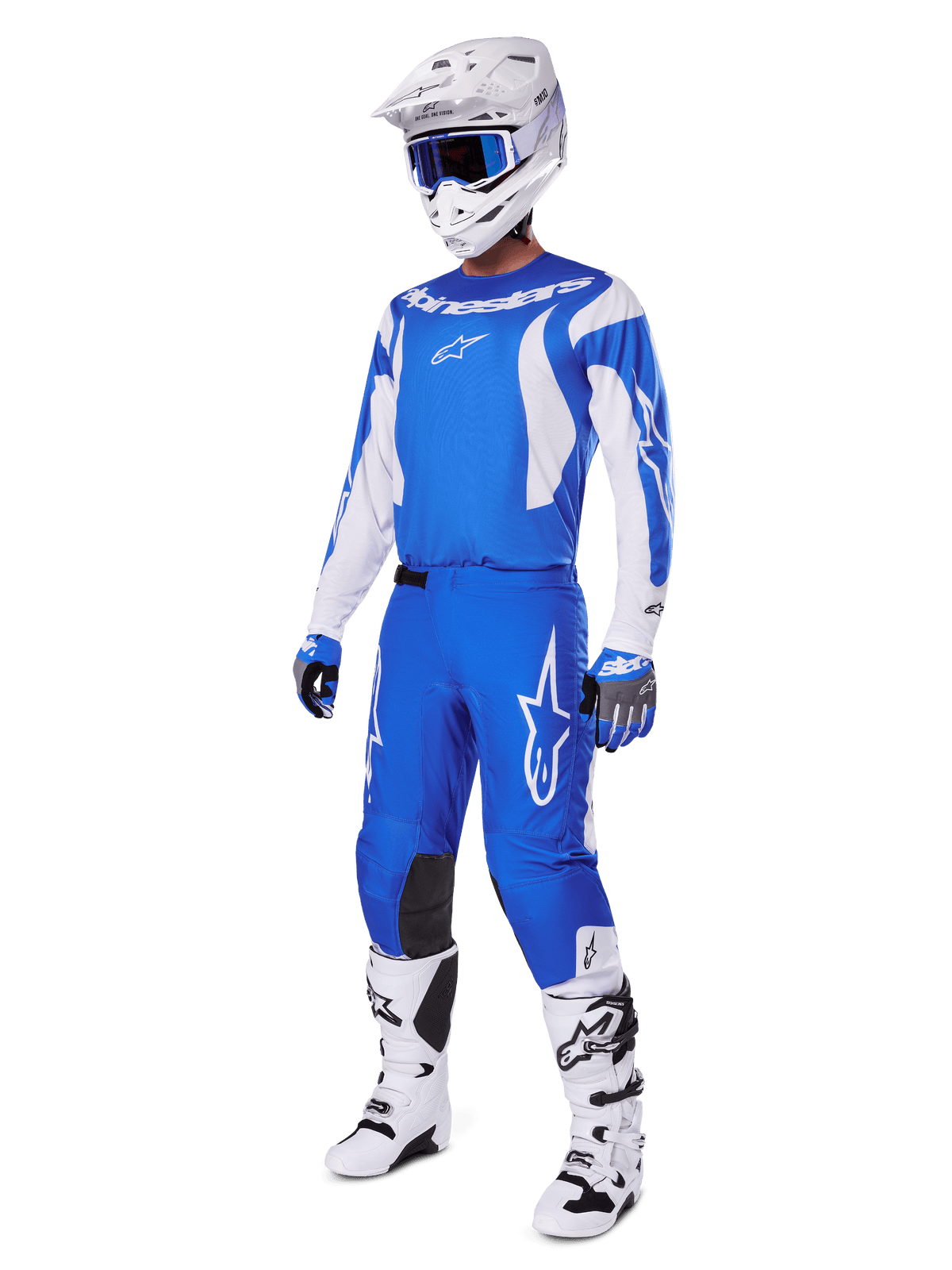 Motorcrosser die de volledige 2025 Fluid Haul Gear Set draagt, blauwe en witte jersey en broek met Alpinestars-branding, witte helm met blauwe bril, witte laarzen en blauwe handschoenen, gecoördineerde race-outfit voor off-road motorcross.