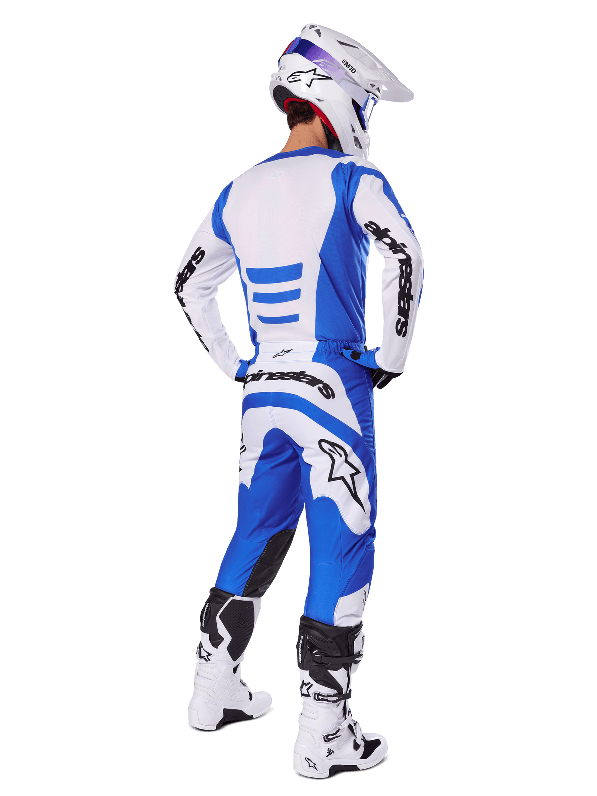 Motorcrosser vanaf de achterkant in de Alpinestars 2025 Fluid Haul Gear Set, blauw-wit jersey met bijpassende broek, witte helm met blauwe accenten en wit-zwarte racelaarzen, gecoördineerde off-road race-outfit