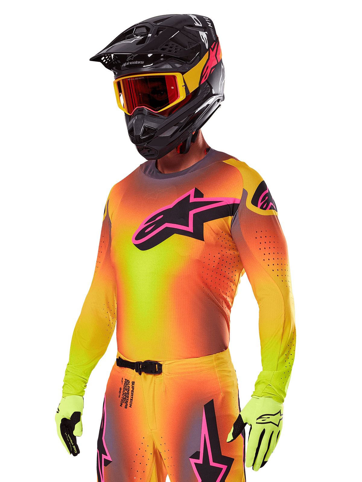 Motocrossrijder in de Alpinestars 2025 Supertech Lipan Gear Set, met een geel en oranje kleurverloop jersey met een roze en zwart Astars-logo, neongele handschoenen en een zwarte helm met rode crossbril, professionele off-road race-uitrusting.