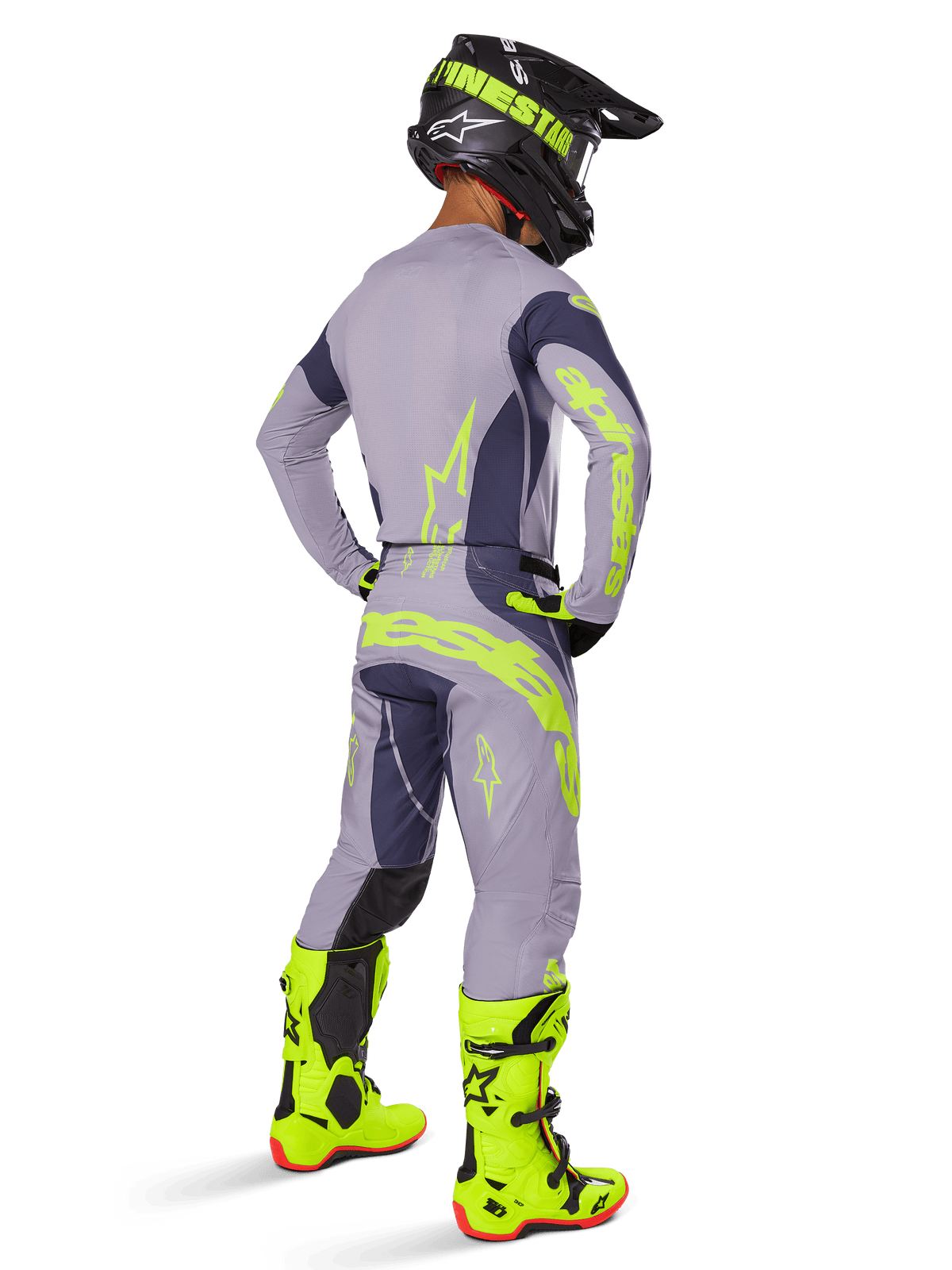 Motocrossrijder van achteren gezien in de Alpinestars 2025 Techstar Dreem Gear Set, grijs en donkergrijs met fluorescerend gele branding, bijpassende jersey en broek, zwarte helm met gele accenten en fel fluorescerend gele laarzen, gecoördineerde professionele motocross-race-outfit.