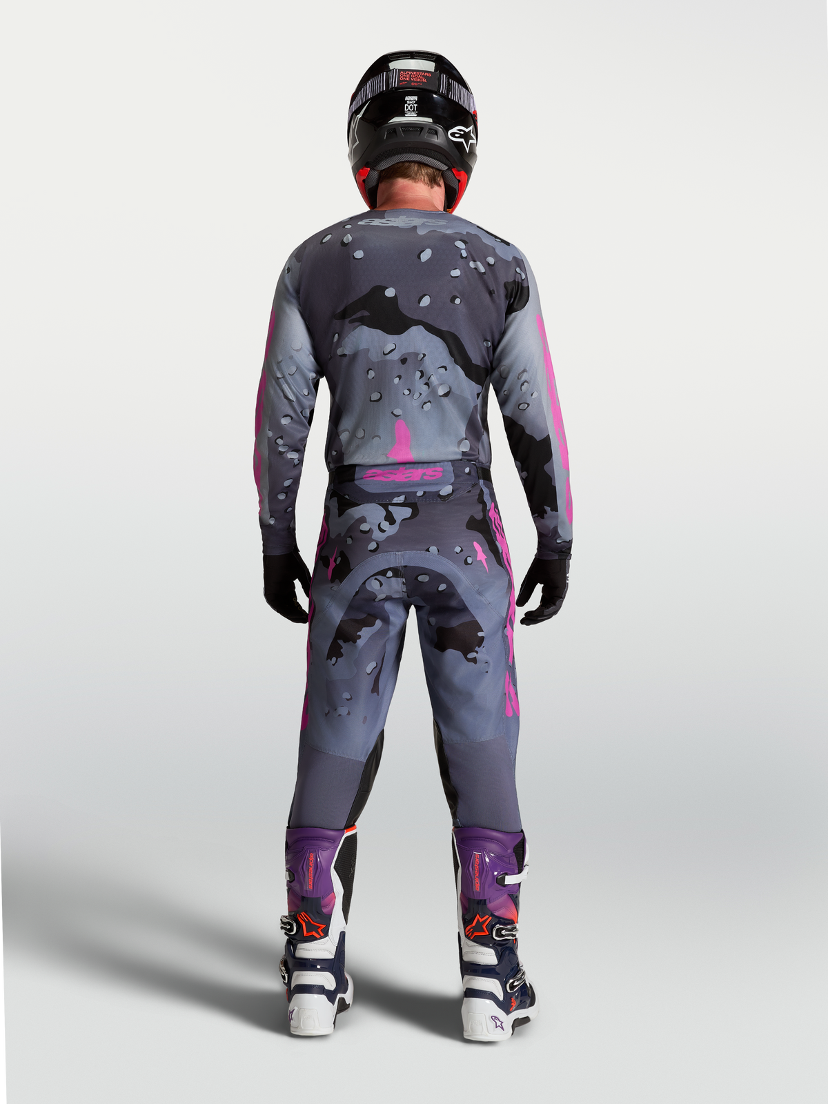 Alpinestars Racer Lone uitrustingsset, grijs en paars camo motorcrossuitrusting, achteraanzicht rijder in bijpassend tenue.