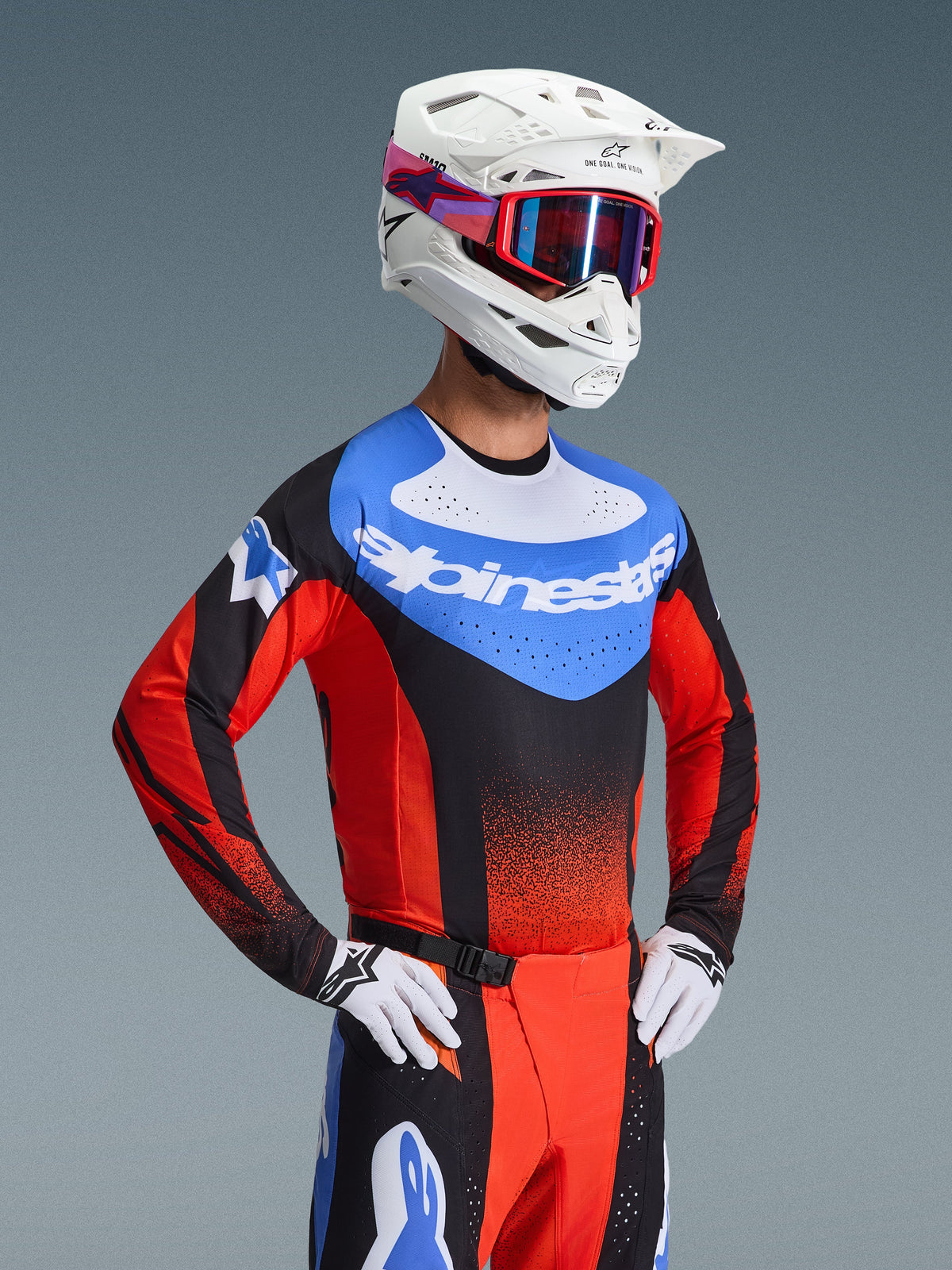 Motorcrosser in Alpinestars 2026 Techstar Knif Gear Set, blauwe jersey met witte branding en rode mouwen, bijpassende zwarte en rode broek met blauwe accenten, witte helm met rode crossbril, wit-zwarte handschoenen, professionele race-outfit voor motorcross