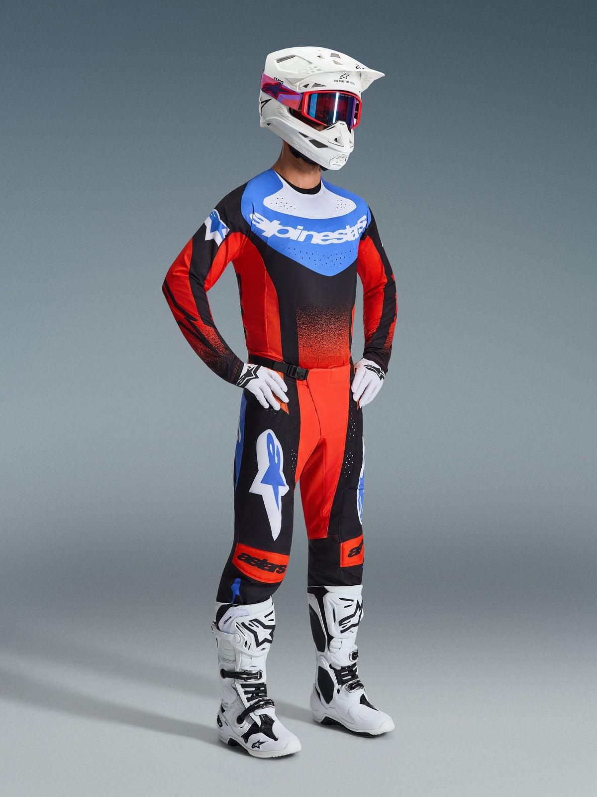 Motocross rider wearing the 2026 Techstar Knif Jersey in Orange, Black, and UCLA Blue, paired with matching motocross pants, white helmet, white and black boots, and white gloves, coordinated professional racing gear for off-road competition