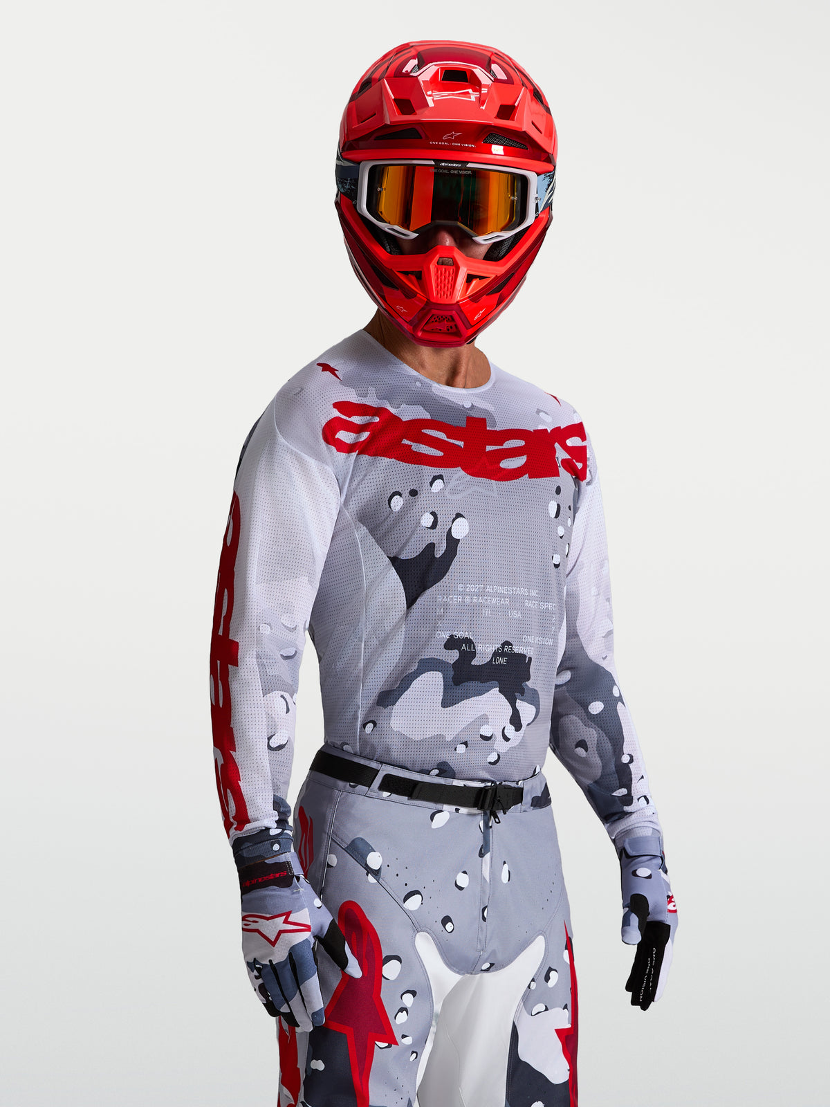 Alpinestars Racer Air Lone jersey, heren-motocrossjersey, grijs camo en rood, ademend mesh, gedragen met helm en crossbril.