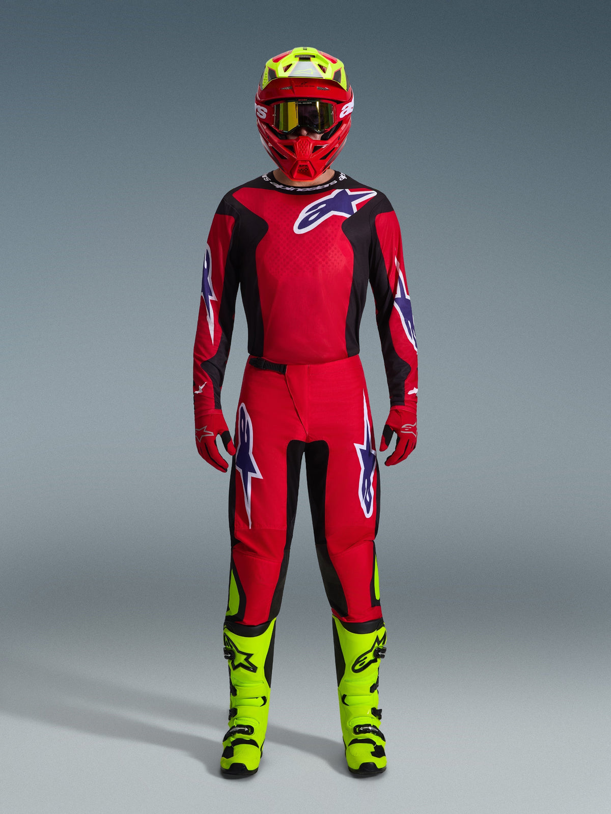 Motorcrosser in de 2026 Fluid Grid Jersey in Rood Zwart Paars, bijpassende rode broek met paarse logo's, rode helm met neongele accenten, neongele laarzen, volledige gecoördineerde race-outfit voor off-road motorcross