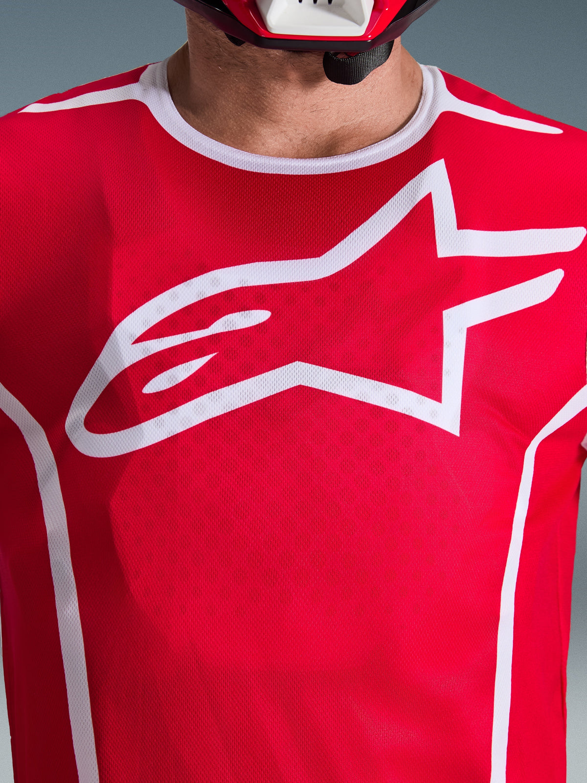 Close-up van de Alpinestars 2026 Fluid Apex Jersey in rood en wit, met een groot wit Astars-logo op de borst, ademende polyfabric mesh-constructie en een witte kraagbies, motorcross racekleding.