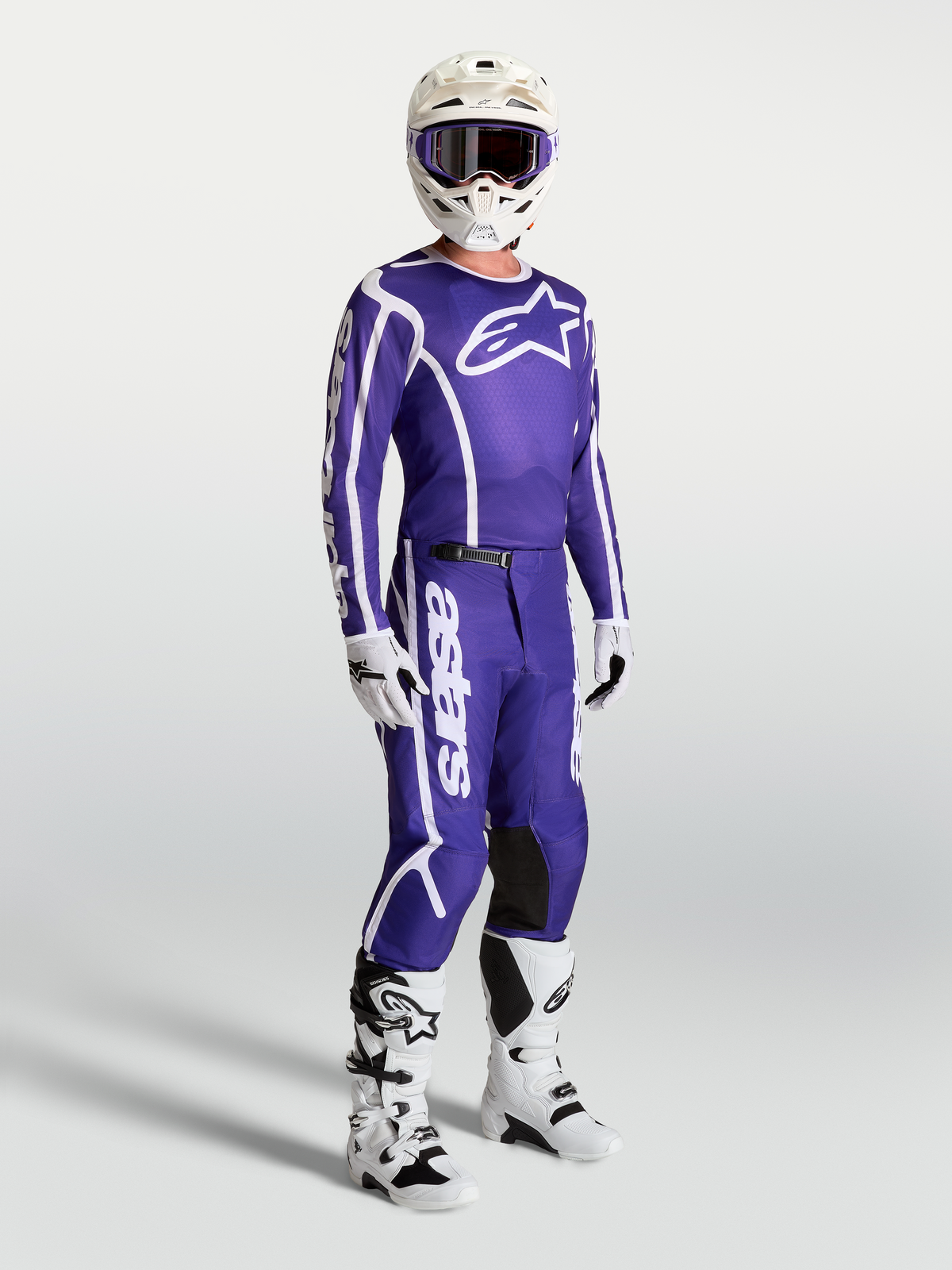 Alpinestars Fluid Apex V2 jersey en broek, blauwe en witte motocross-set op model met witte motorlaarzen en helm.