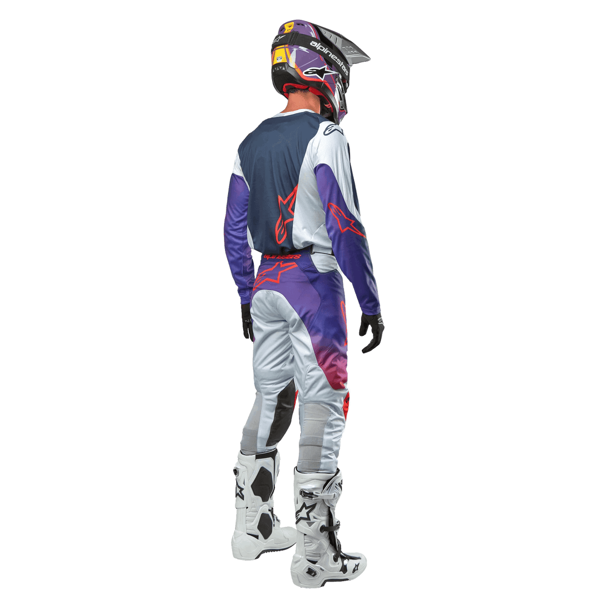 Alpinestars 2024 Racer Hoen motorcross outfit, achteraanzicht, lichtgrijze broek met paarse en oranje accenten, donkerblauwe jersey met rode logo's, witte motorcrosslaarzen, persoon draagt volledige motorcross uitrusting