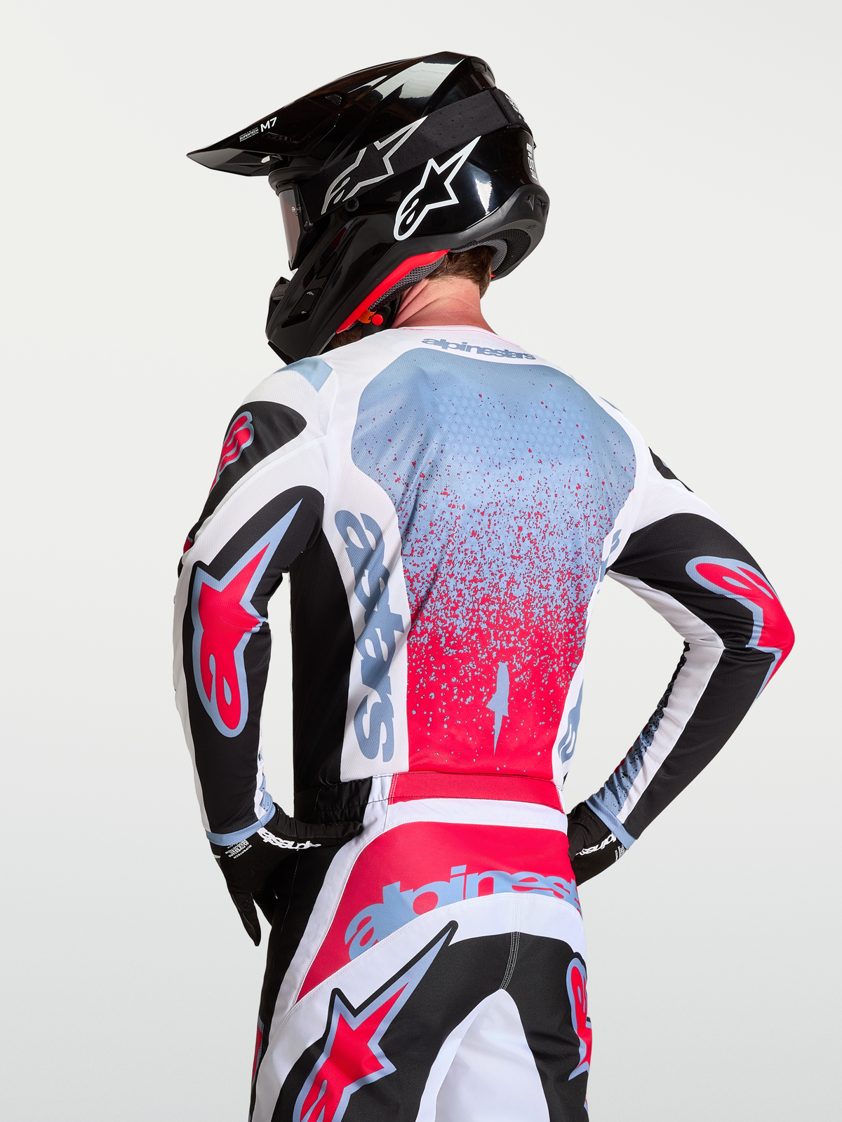 Alpinestars Fluid Drag jersey op een rijder met motocrosshelm, zwart, wit en rood met lichtblauwe details.