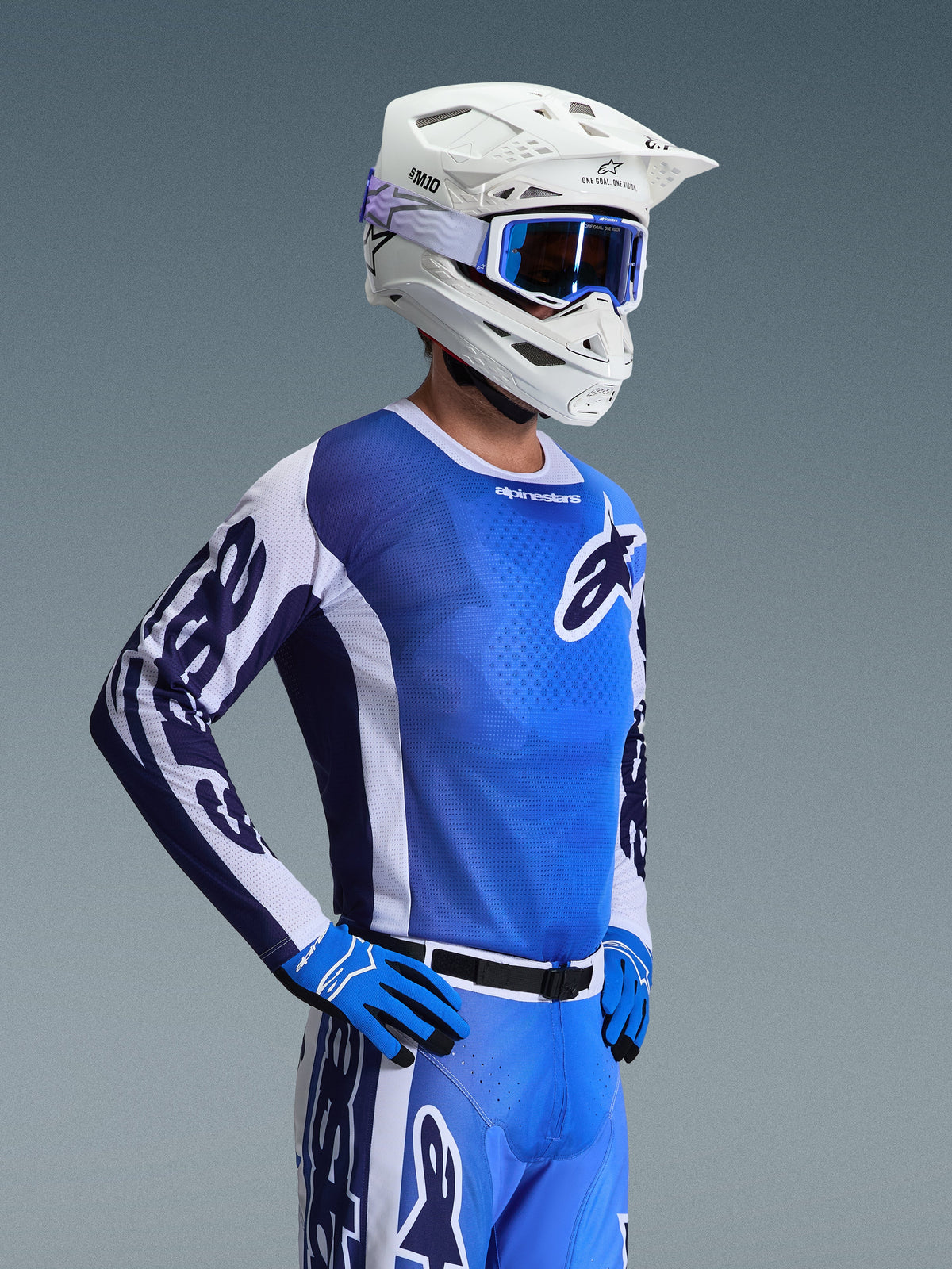 Alpinestars 2026 Racer Air Portl Jersey, motorcross shirt, Ucla blauw en wit, gedragen met een witte helm, blauwe crossbril en bijpassende handschoenen, voorzien van een ademend mesh-ontwerp voor off-road racing bij hoge temperaturen.