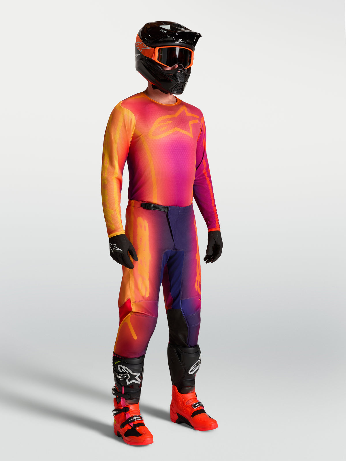 Alpinestars Fluid Kepler Jersey, paars en oranje motorcross jersey op een model met bijpassende race-uitrusting.