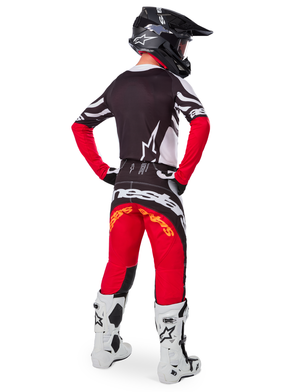 Achteraanzicht van een motorcrosser die de Limited Edition Techstar Deep Gear Set draagt, met een zwarte jersey met witte en rode accenten, een bijpassende rode en zwarte broek met Alpinestars-branding, witte racelaarzen en een zwarte helm, die de volledige off-road race-outfit toont.