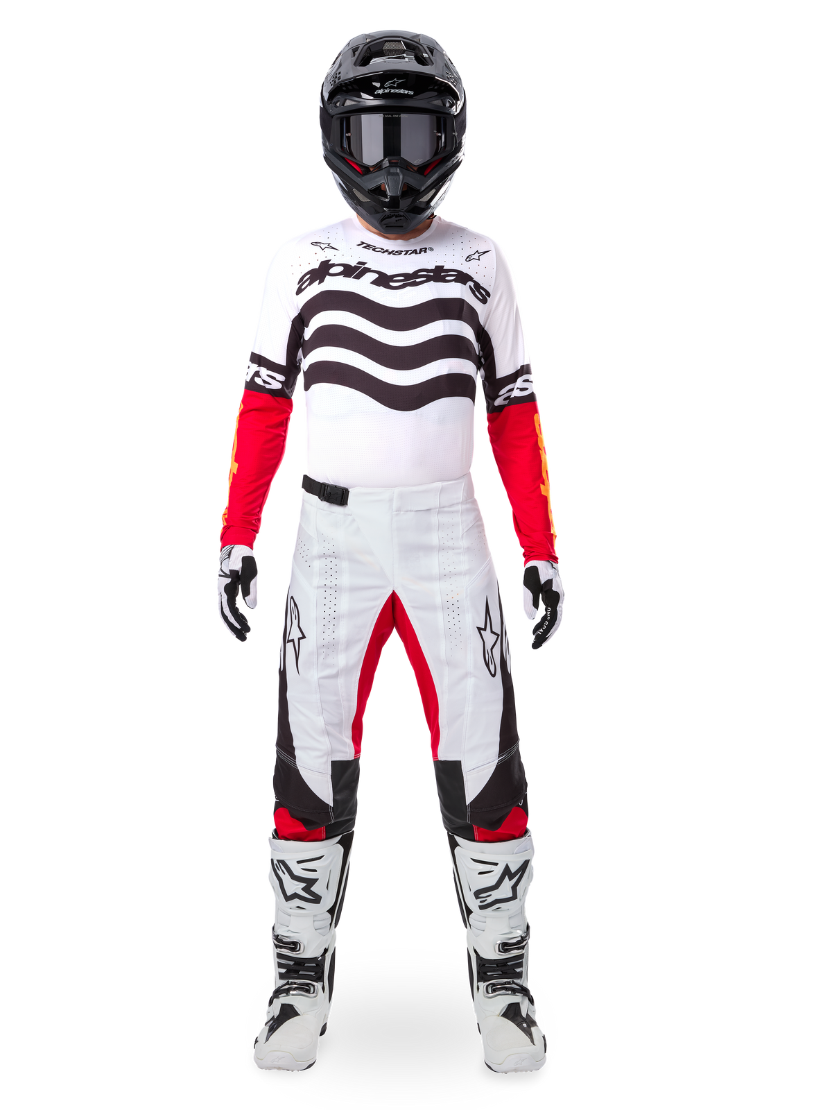 Motorcrosser in de Alpinestars Limited Edition Techstar Deep-uitrustingsset, wit jersey met zwarte golfafbeeldingen en rode mouwen, bijpassende wit-zwarte broek met rode accenten aan de binnenzijde van de dijen, zwarte helm met donkere bril en witte laarzen, volledige professionele off-road race-outfit