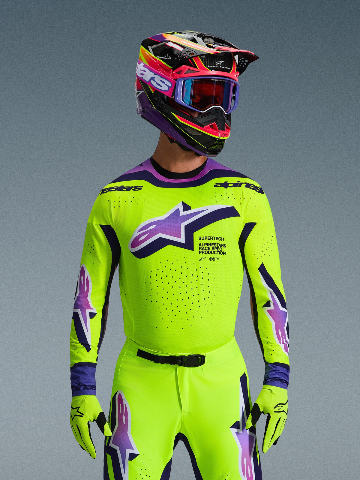 Alpinestars 2026 Supertech Vista Jersey, motorcross shirt, fel neongeel met paarse en zwarte accenten, gedragen met bijpassende motorcrosshelm, crossbril en handschoenen, pro-level atletische pasvorm voor off-road racing