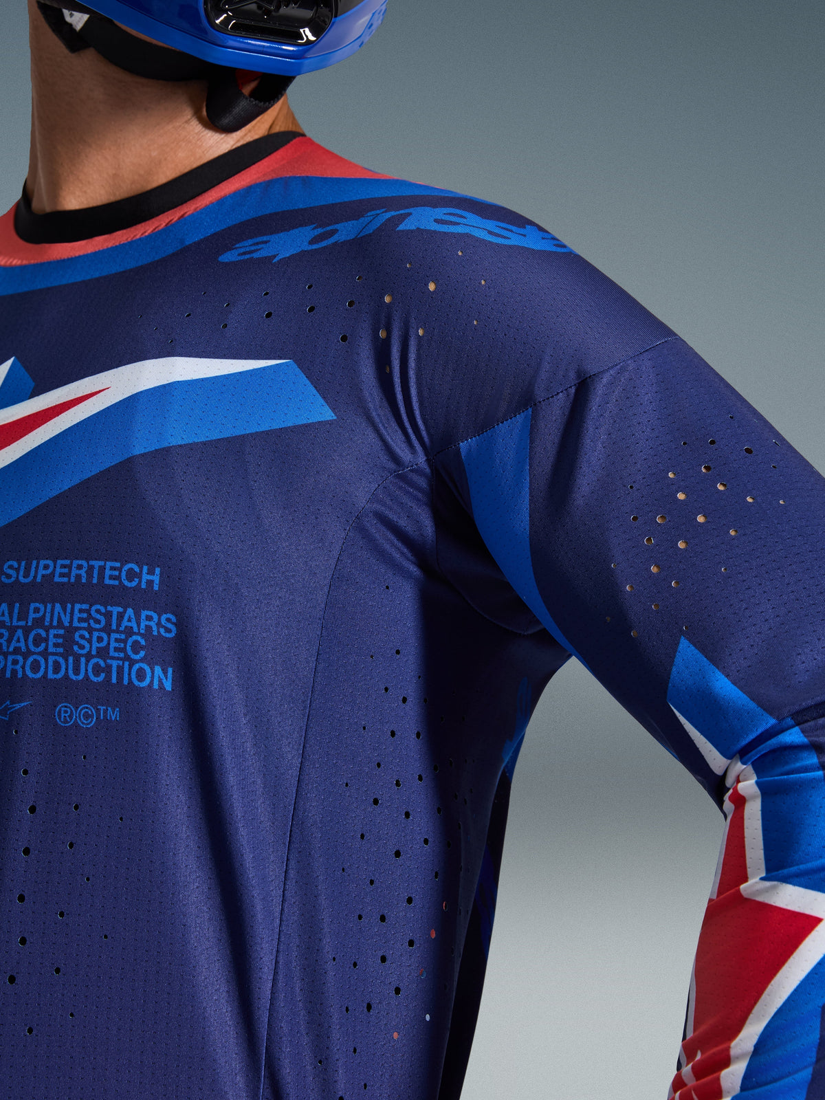 Alpinestars 2026 Supertech Vista Jersey, Close-up of Dark Navy and Cobalt blue jersey with Hot Coral collar, featuring laser-cut ventilation perforations and Alpinestars Race Spec branding, premium athletic mesh construction for motocross racing