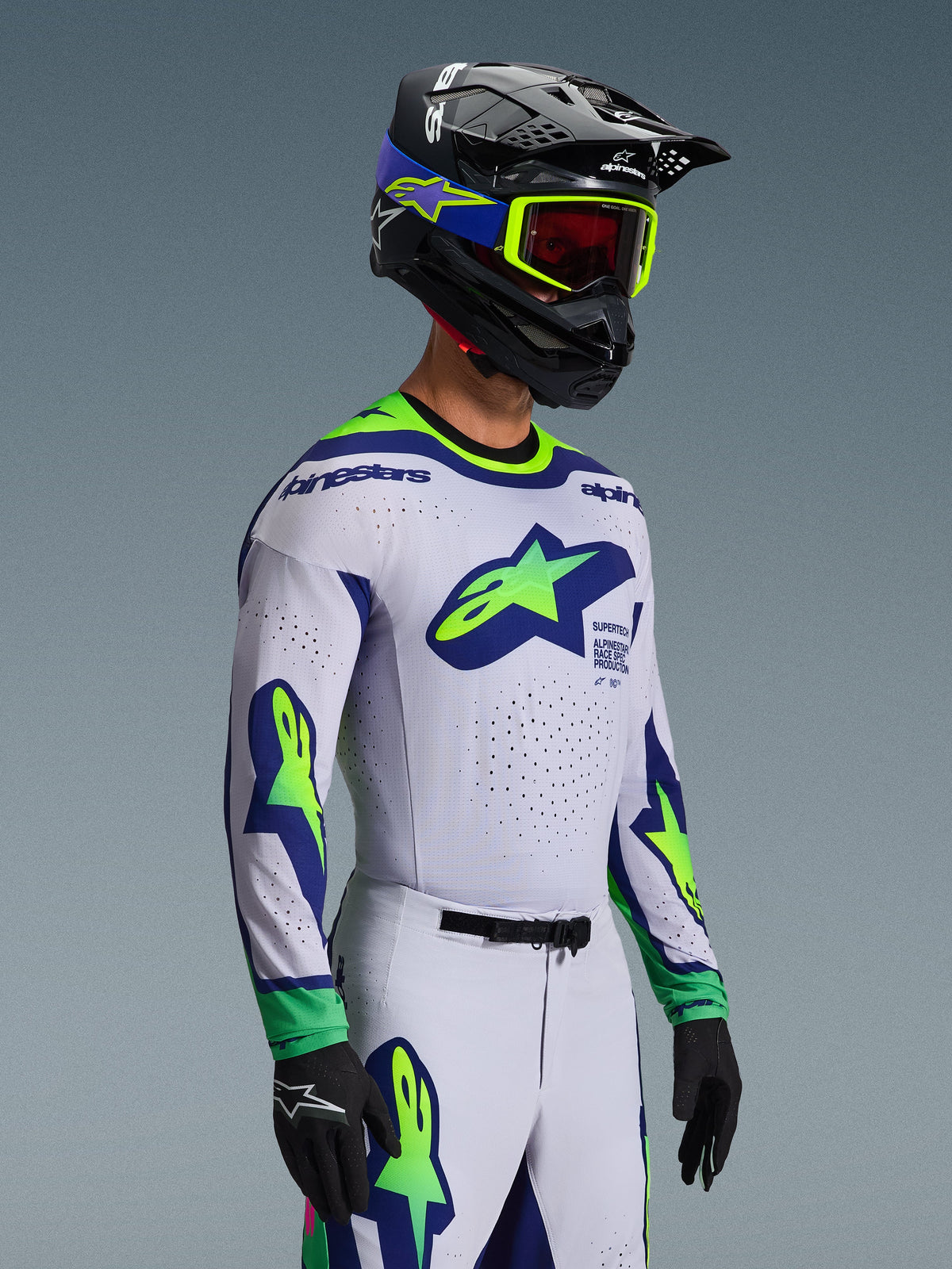Motorcrosser in de 2026 Supertech Vista Jersey in lichtgrijs met fluogeel en blauwe accenten, met grote sterlogo's op de borst en mouwen, bijpassende broek en helm met fluogele bril, zwarte handschoenen, professionele motorcrossuitrusting