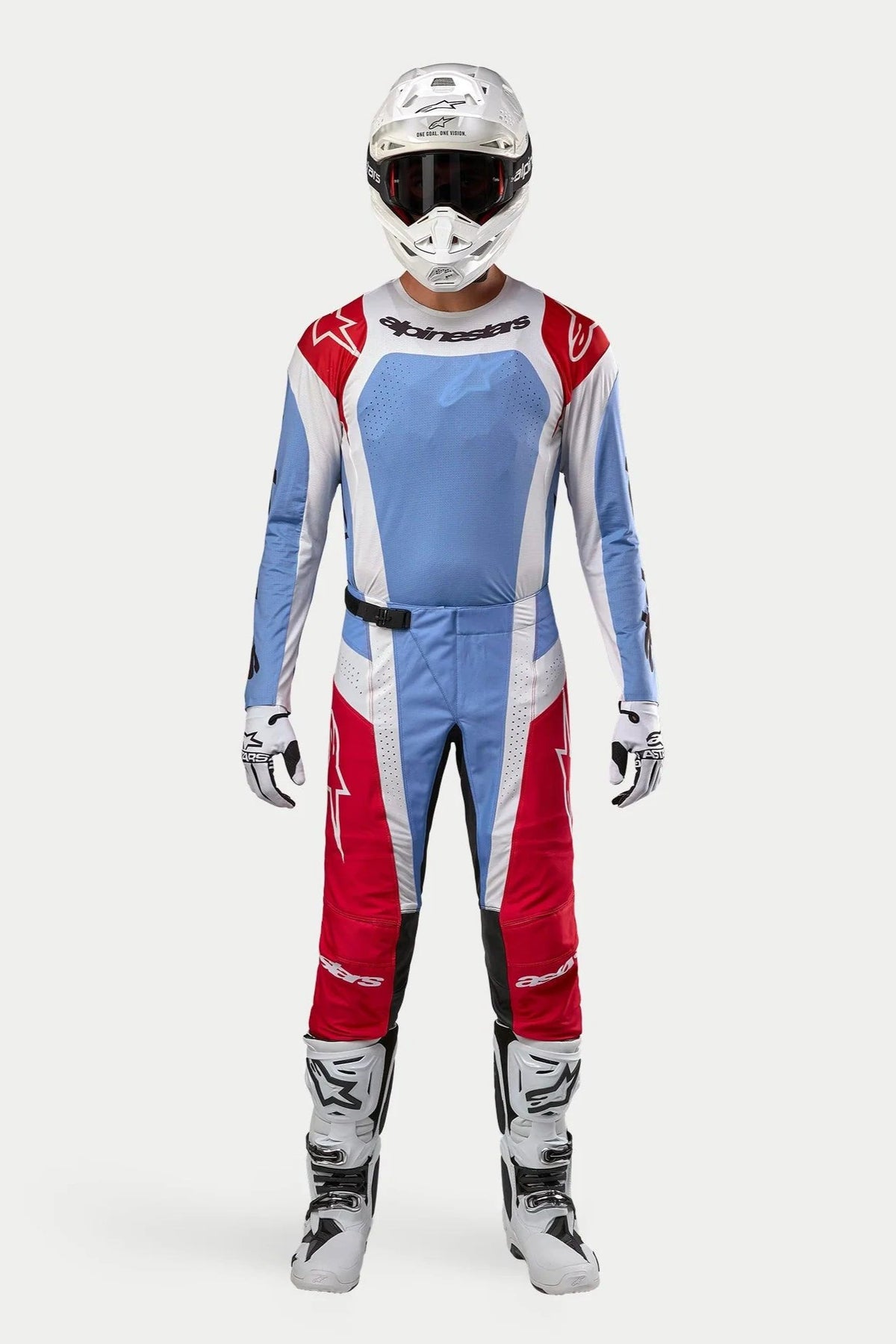 Motorcrossrijder in de volledige 2024 Alpinestars Techstar Ocuri-kit, lichtblauw, Marsrood en wit shirt en broek, gecombineerd met een witte helm, witte laarzen en handschoenen, professionele race-uitrusting voor off-road motorcross