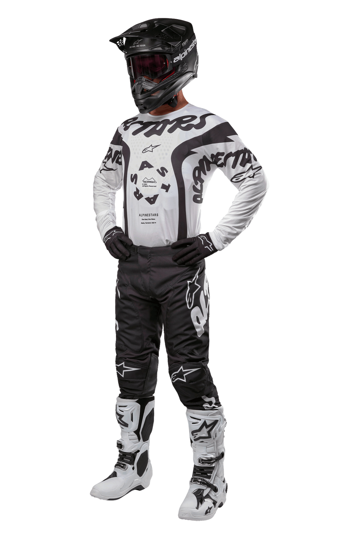 Motocross rider wearing full gear featuring the Alpinestars 2024 Racer Hana Jersey in white and black, black motocross pants with white logos, black helmet, white and black racing boots, and black gloves, professional off-road racing outfit
