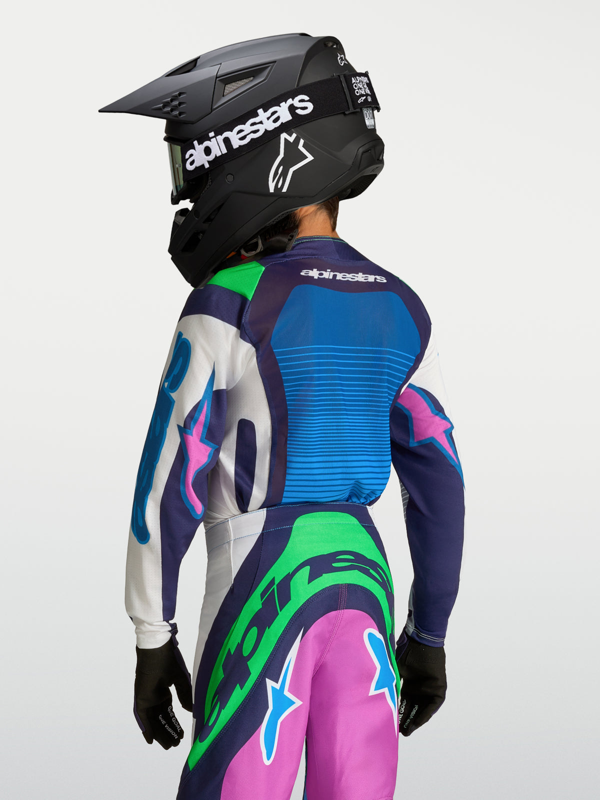 Alpinestars Jeugd Supertech Maven Jersey, blauwe en groene motocrossjersey voor jongeren, achteraanzicht met helm.