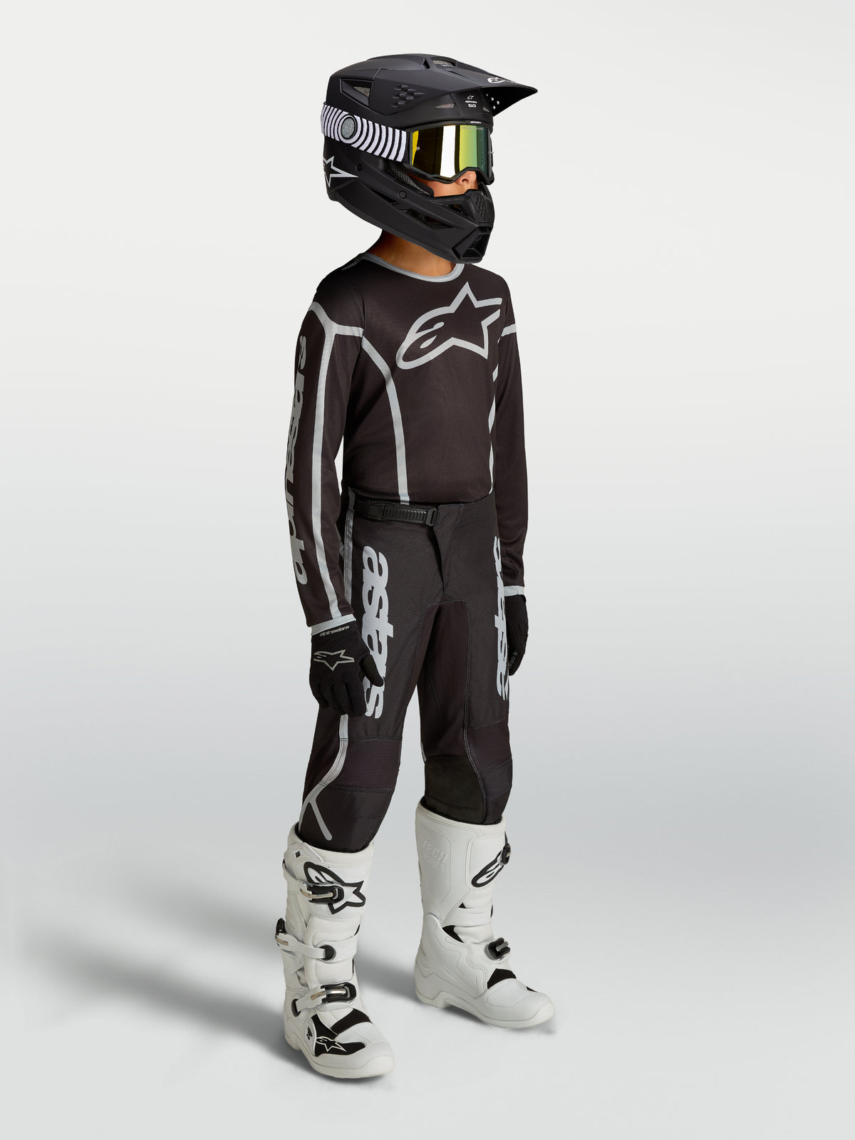 Alpinestars Jeugd Fluid Apex V2 jersey en uitrustingsset, zwart en zilver, motocrossoutfit gedragen door een jong model.