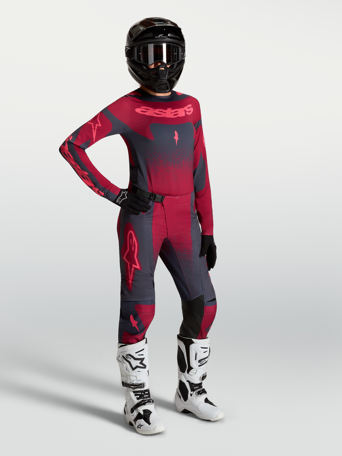 Alpinestars Stella Techstar Swan broek en jersey, dames motocross-outfit in karmijnrood en donkergrijs met witte motorlaarzen.