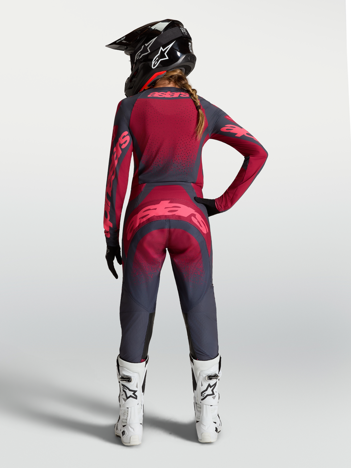 Alpinestars Stella Techstar Swan gearset en broek, dames motocross-outfit in grijs en rood, achteraanzicht met witte laarzen.