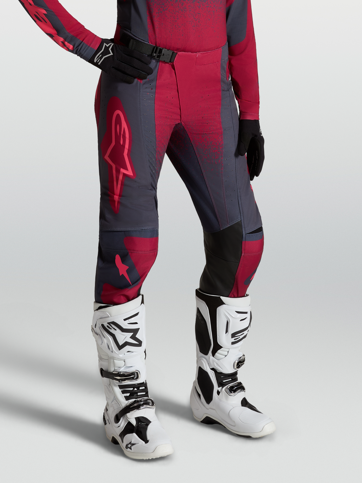 Alpinestars Stella Techstar Swan broek, dames-motocrossbroek, rood en donkergrijs, gedragen met witte Tech 10 motorlaarzen.