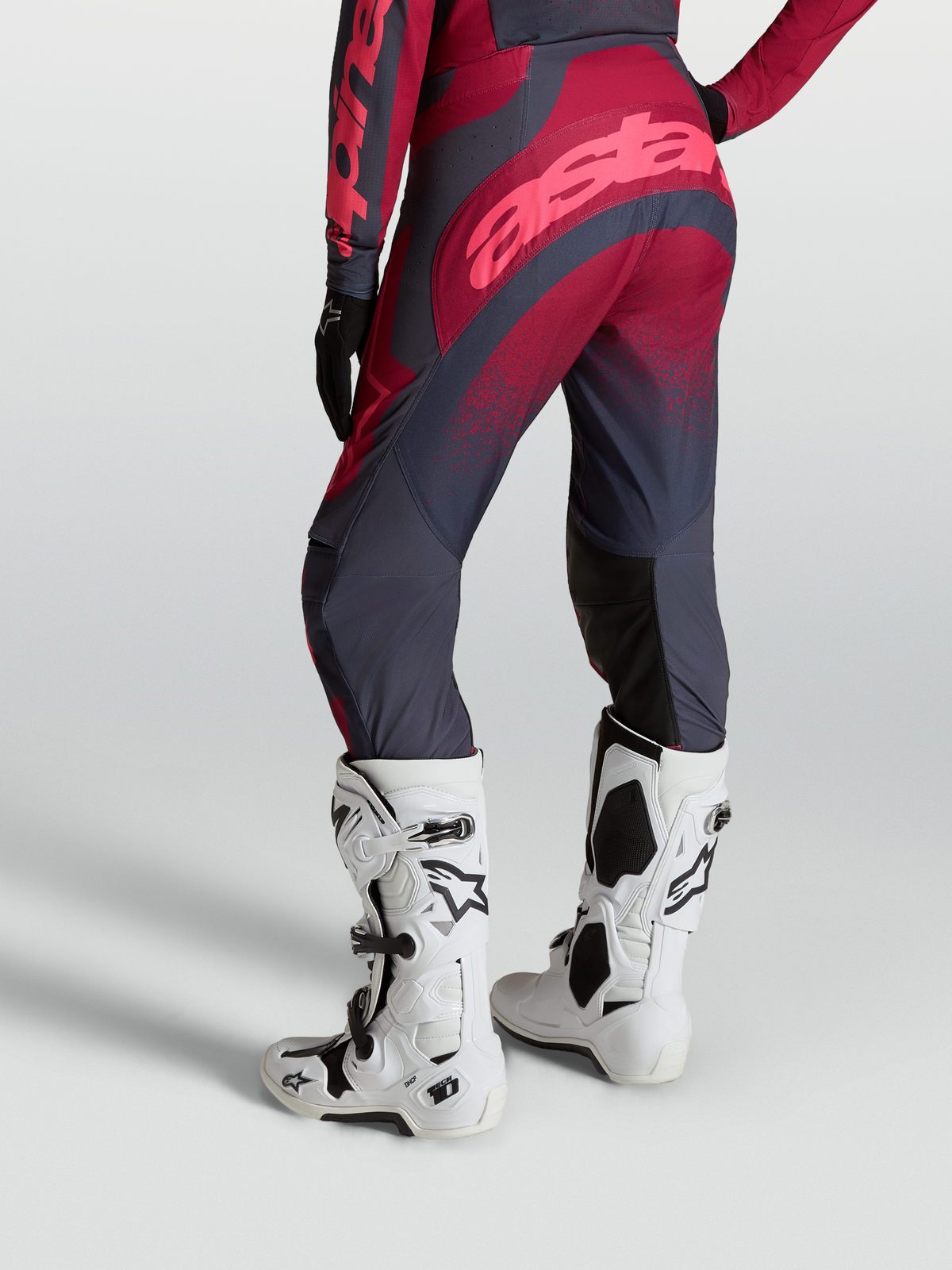 Alpinestars Stella Techstar Swan Broek van achteren gezien, met crimson en donkergrijze panelen en witte Tech 10 motorlaarzen.