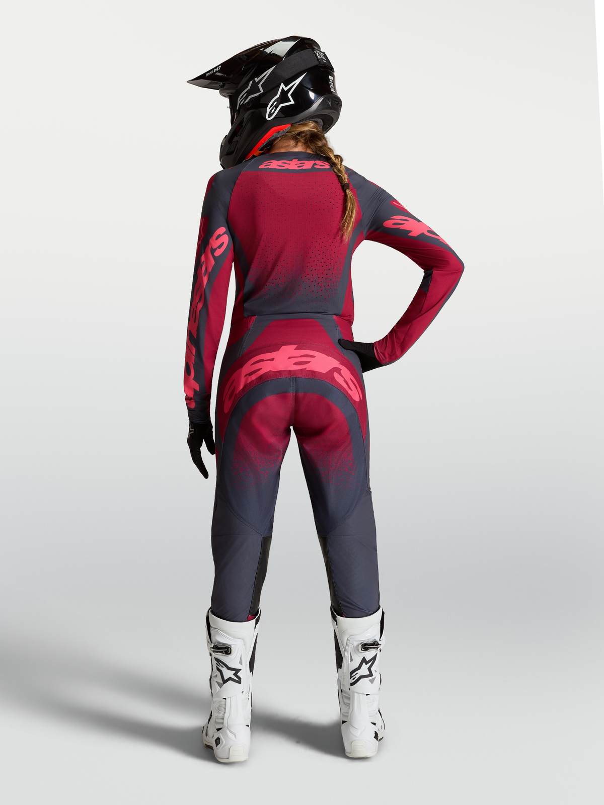 Alpinestars Stella Techstar Swan Jersey, dames motorcrossjersey, donkerrood en donkergrijs, geventileerde constructie, achteraanzicht op model met bijpassende mx-broek en witte laarzen.