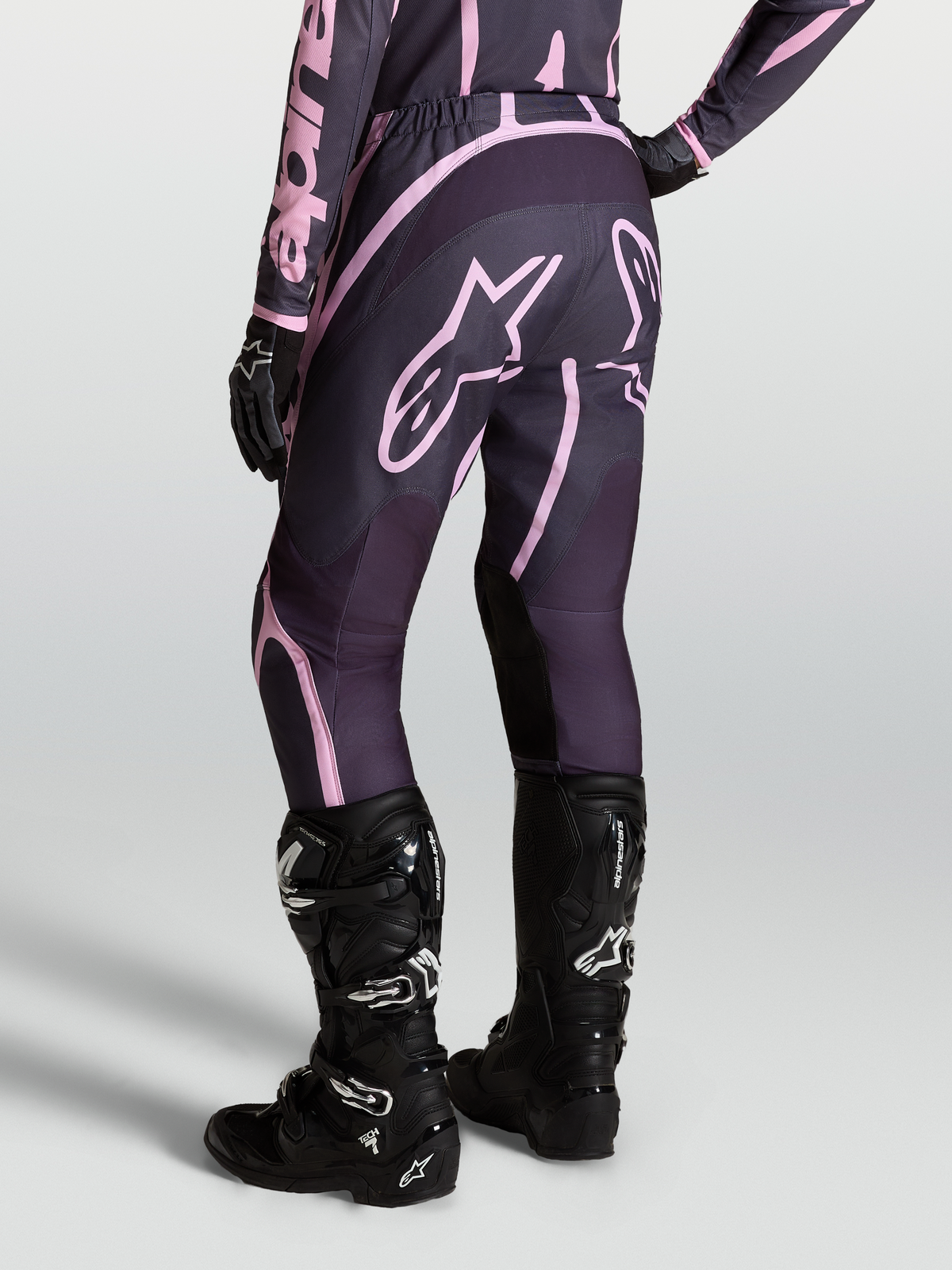 Alpinestars Stella Fluid Apex V2 broek, dames motorcrossbroek in grijs en roze, gedragen met zwarte Tech 7 laarzen.
