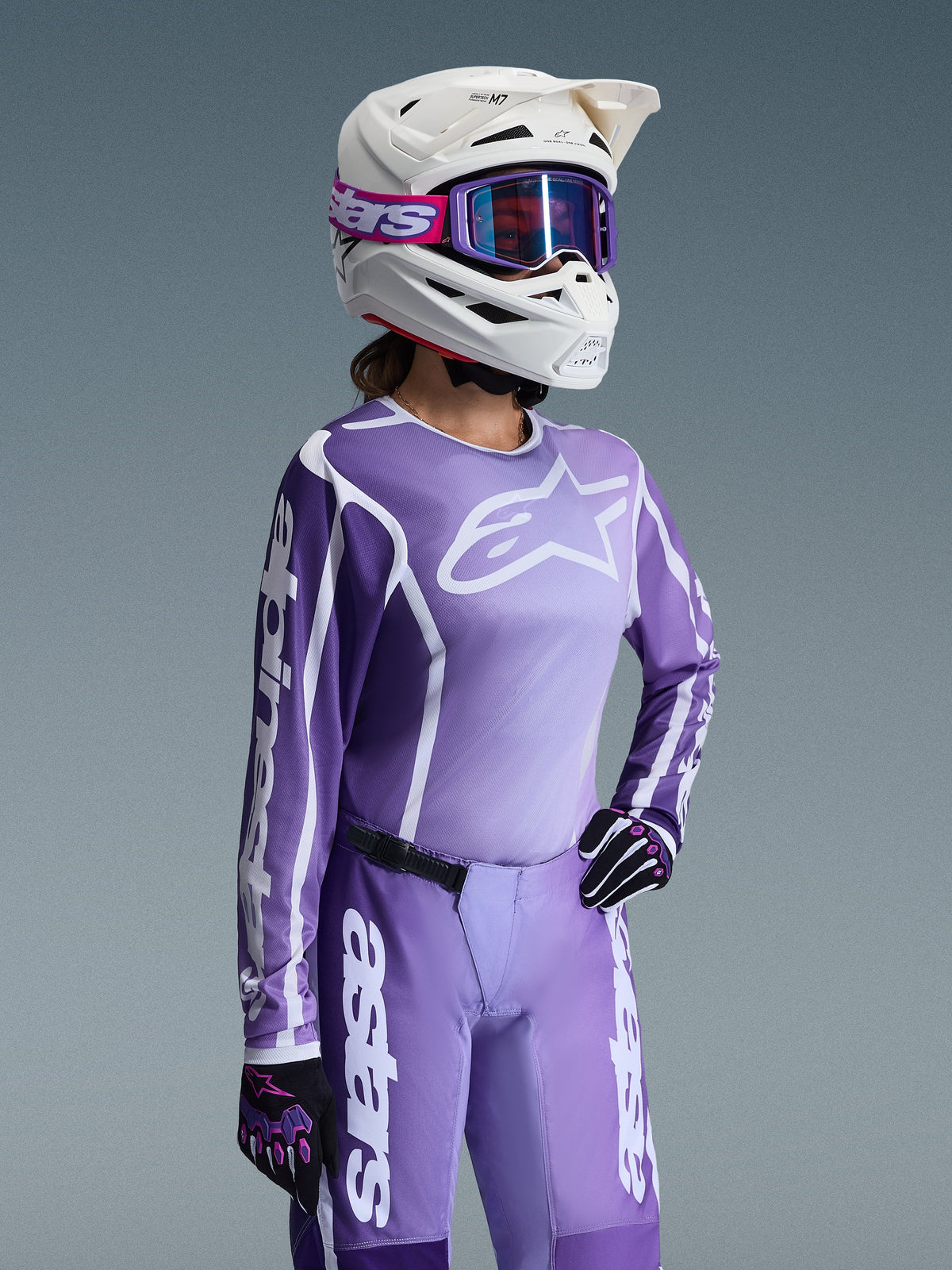 Alpinestars 2026 Stella Fluid Apex gear-set voor dames, paars en lavendelkleurig motocross-shirt en crossbroek, gedragen door een rijder met een witte helm en paarse crossbril, voorzien van opvallende witte Alpinestars-branding en logo's