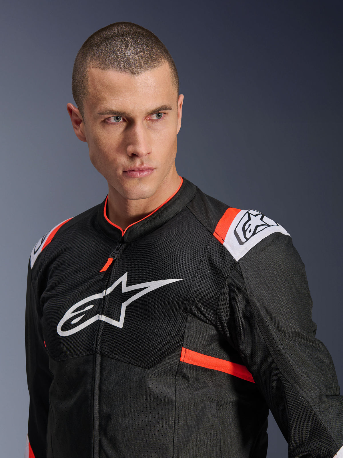 Alpinestars T-SPS Air v2 Jas, zwart met witte en Red Fluo accenten, mesh textielconstructie voor luchtstroom, groot wit Alpinestars-logo op de borst, gedragen door model, stedelijke sportieve rijstijl