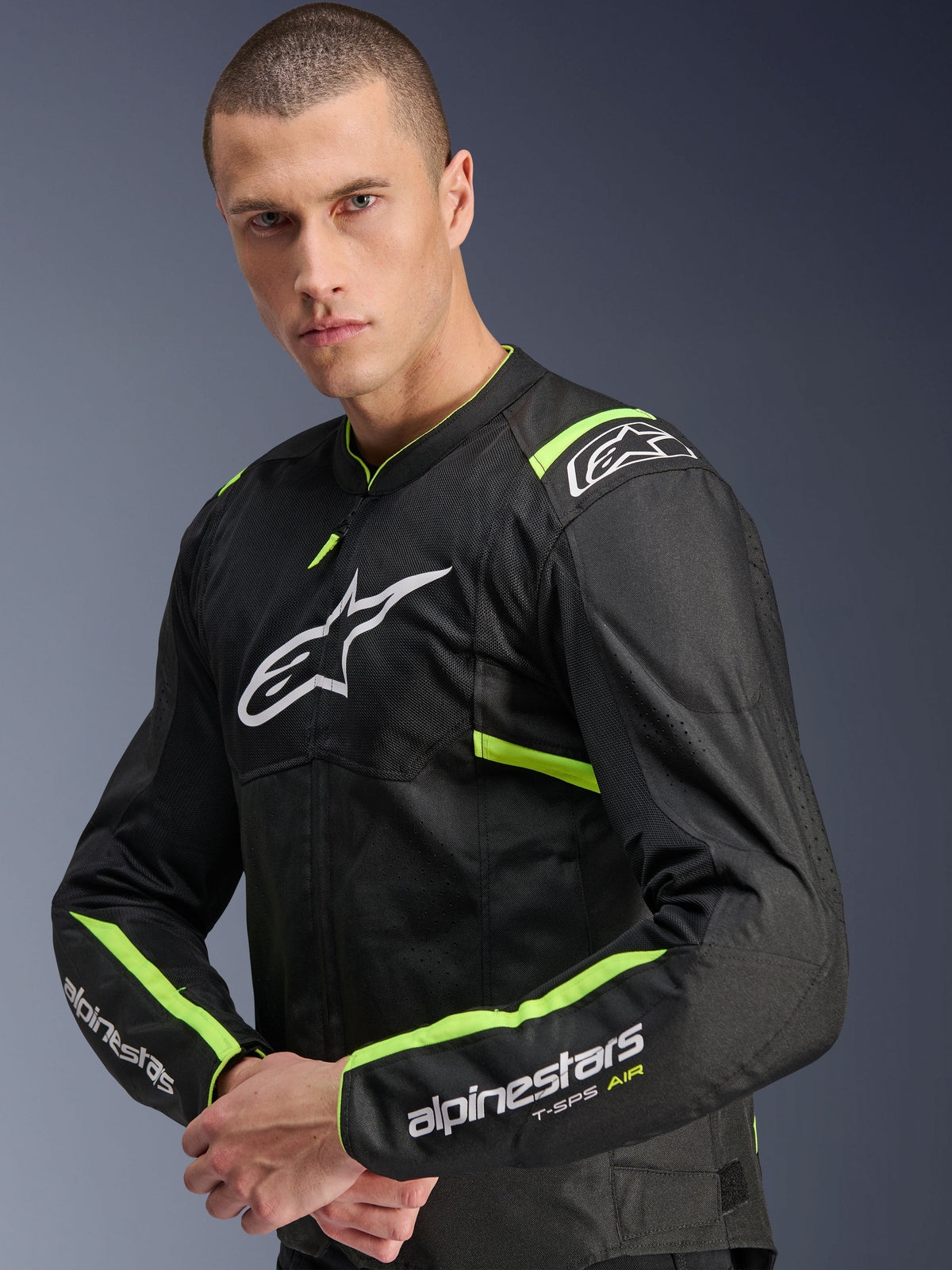 Alpinestars T-Sps Air V2 Jas, Black Yellow Fluo, textiele motorjas gedragen door een model, voorzien van tech mesh-panelen voor luchtstroom, wit Alpinestars-logo op de borst en fluo gele accenten op de schouders en mouwen.