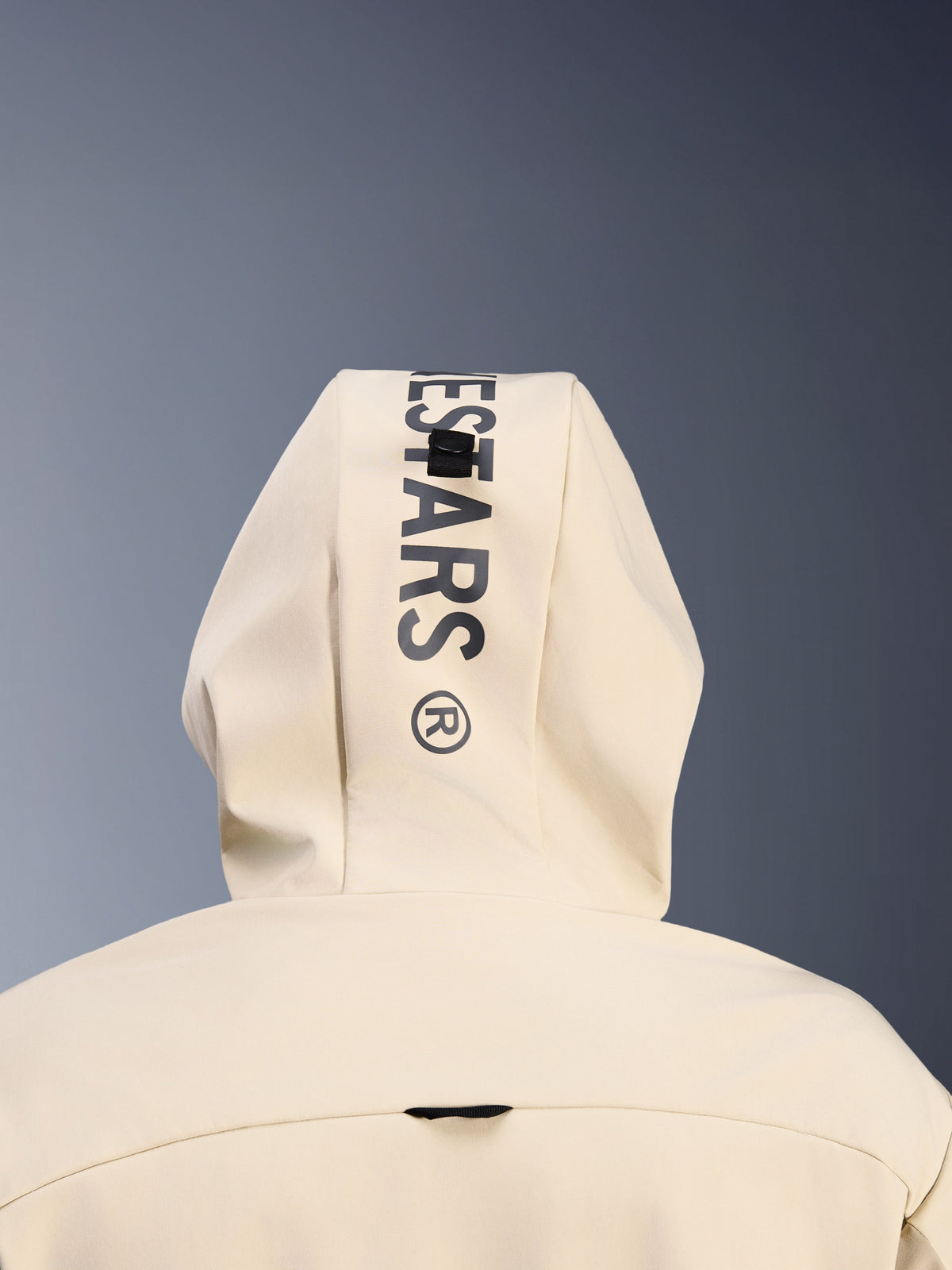 Alpinestars Radium Tech Hoodie in Mastic Aluminum, close-up achteraanzicht van de capuchon met verticale zwarte Alpinestars-branding en het bevestigingslussysteem voor de capuchon, detail van stedelijke motorkleding