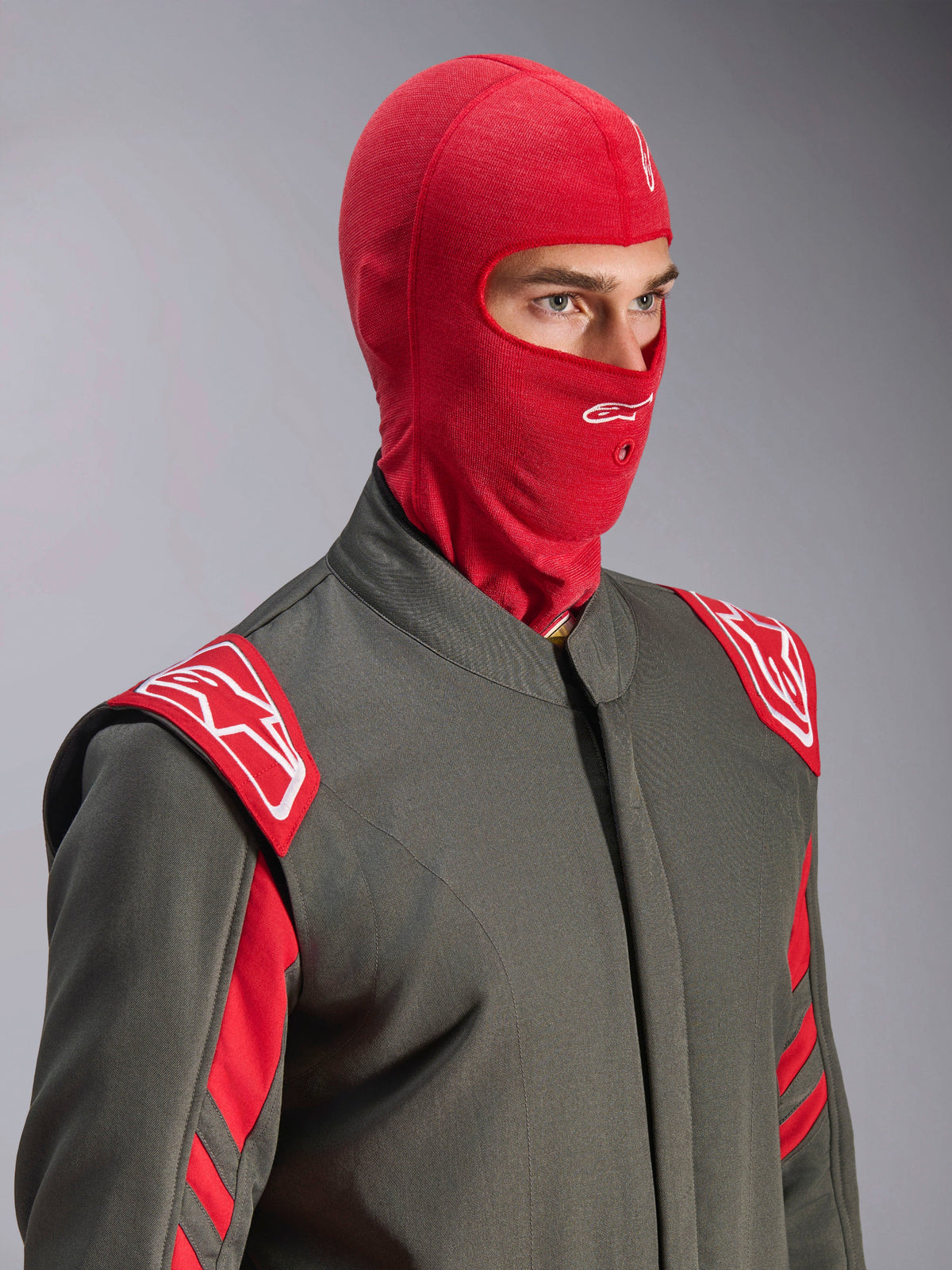Alpinestars ZX Evo V3 bivakmuts, rood, gedragen door een coureur in een grijs racepak met rode en witte accenten, met een wit Astars-logo op het voorhoofd en een opening voor een hydratatiebuis, vlamvertragende onderlaag voor autoraces