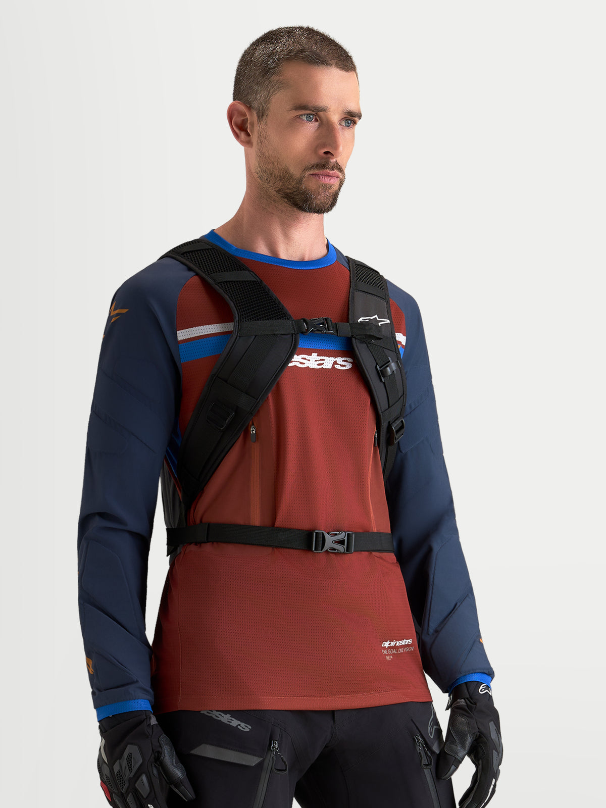 Alpinestars AT-9 rugzak, motocrossrugzak in zwart, gedragen door een mannelijk model met zicht op het gewatteerde harnas van de schouderbanden en het borstbandsysteem