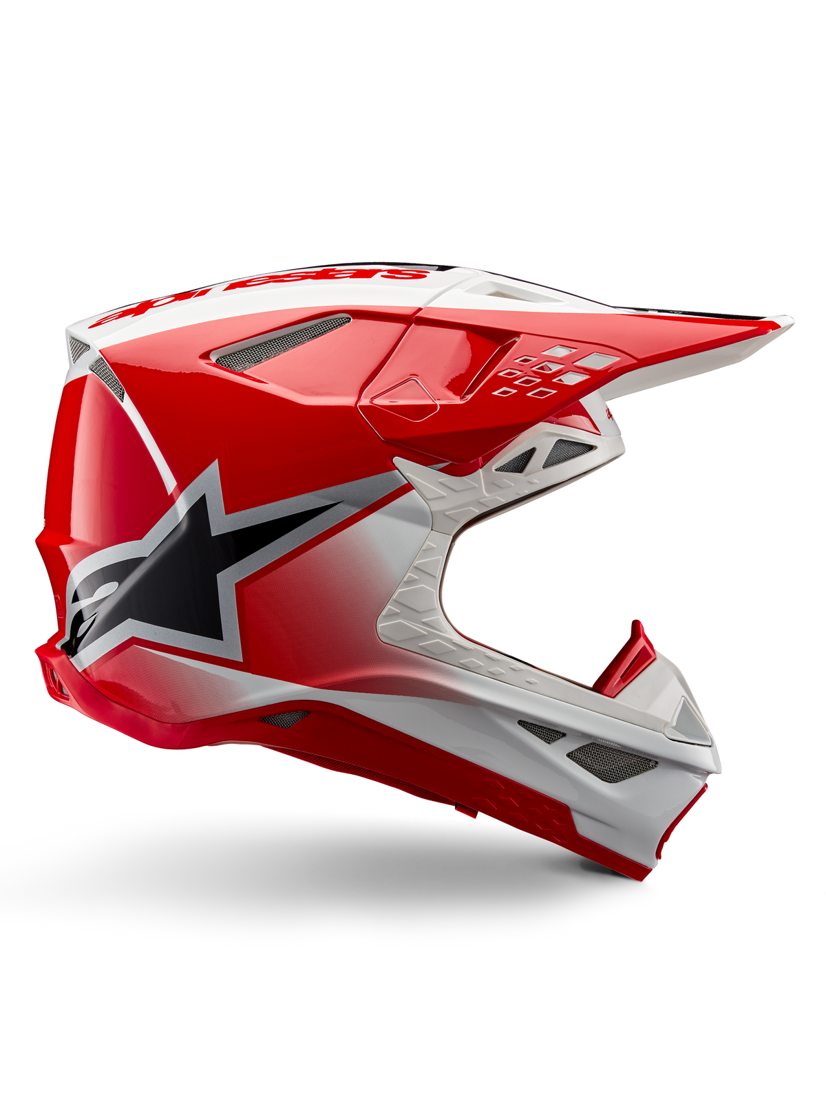 Alpinestars Supertech M10 Unite helm, motorcross racehelm, rood en wit glanzend, zijaanzicht met hoekige geometrische patronen, zwarte ster-graphic, meerdere mesh ventilatieopeningen, aerodynamisch ontwerp voor off-road racing